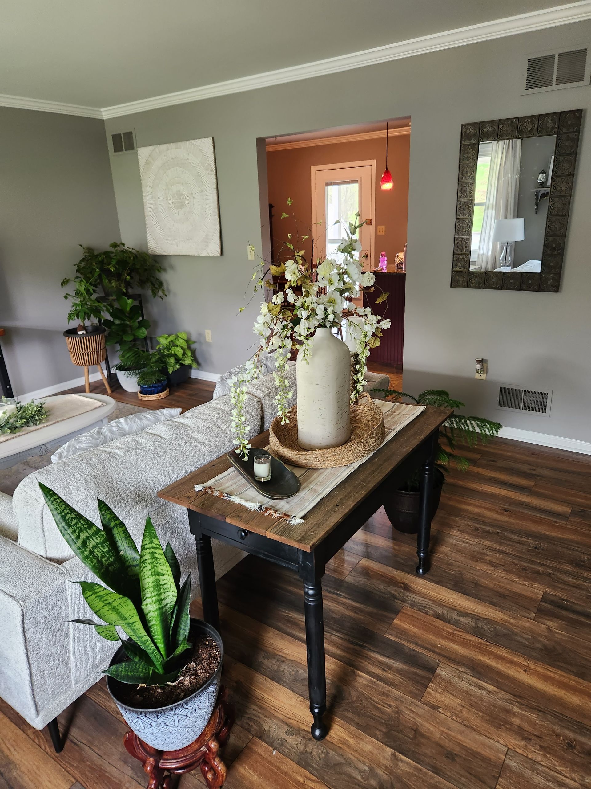 A living room with a couch , chair , table and plants.