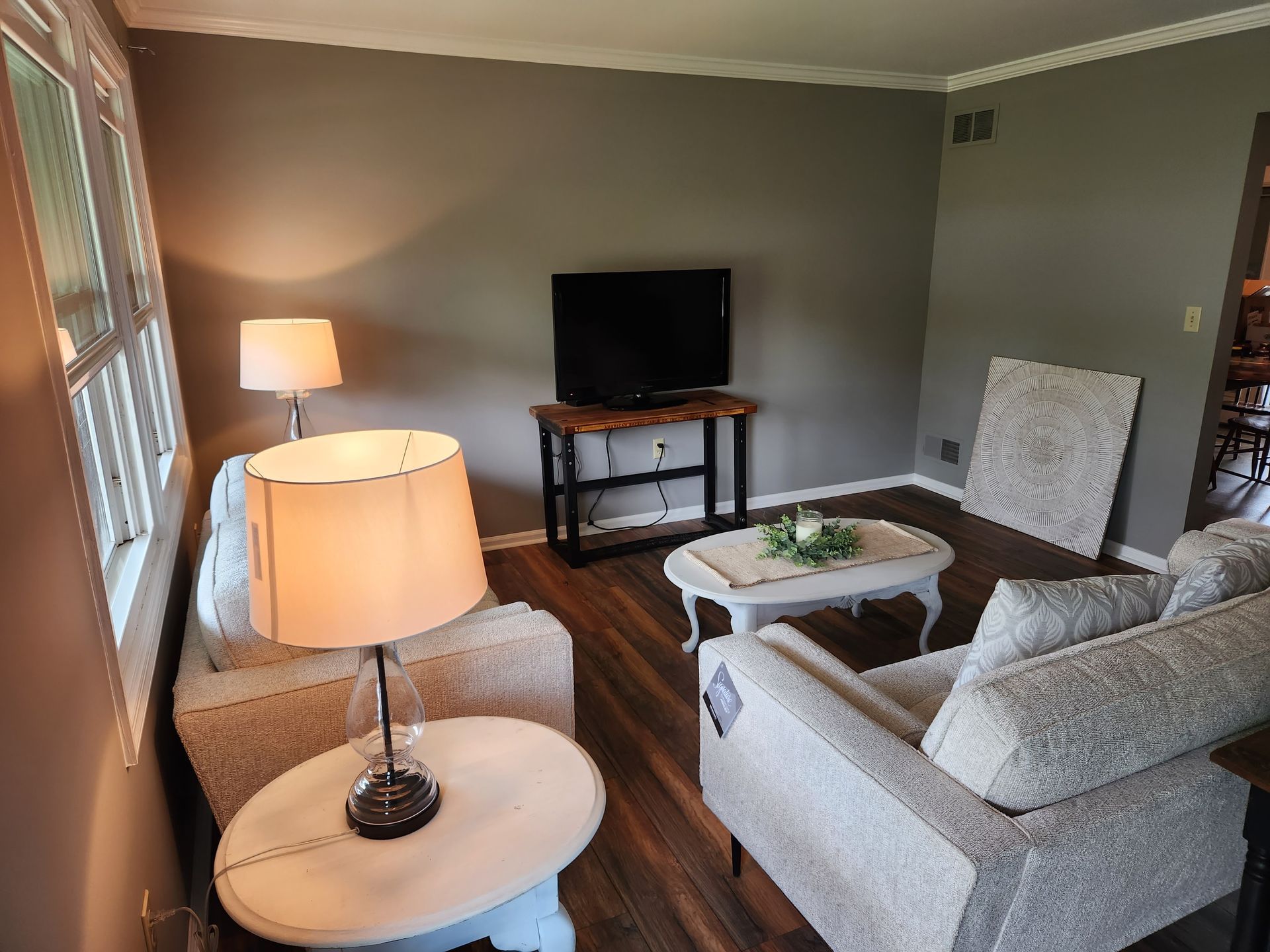 A living room with a couch , chair , table , lamp and television.