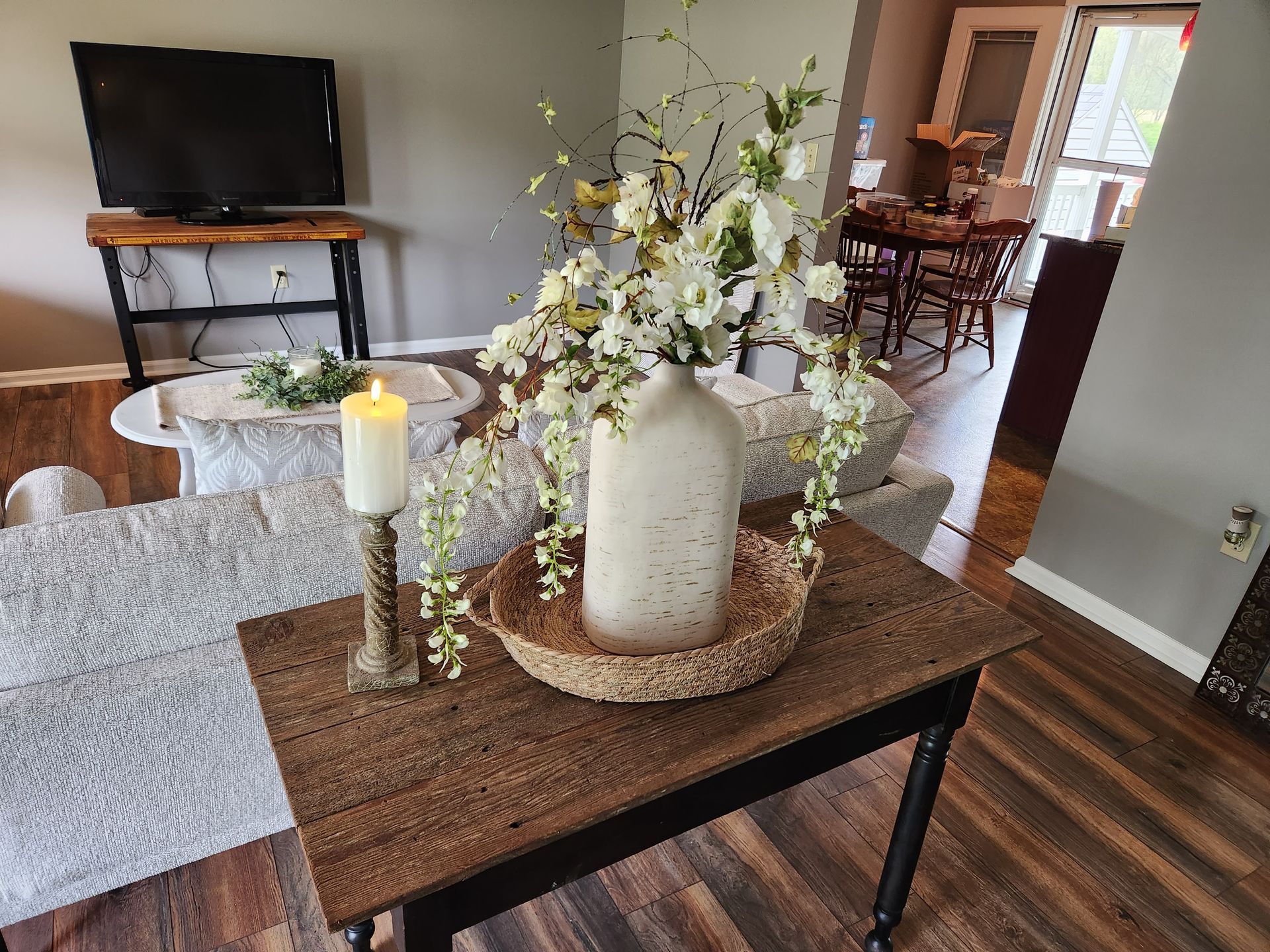 A table with a vase of flowers and a candle on it in a living room.