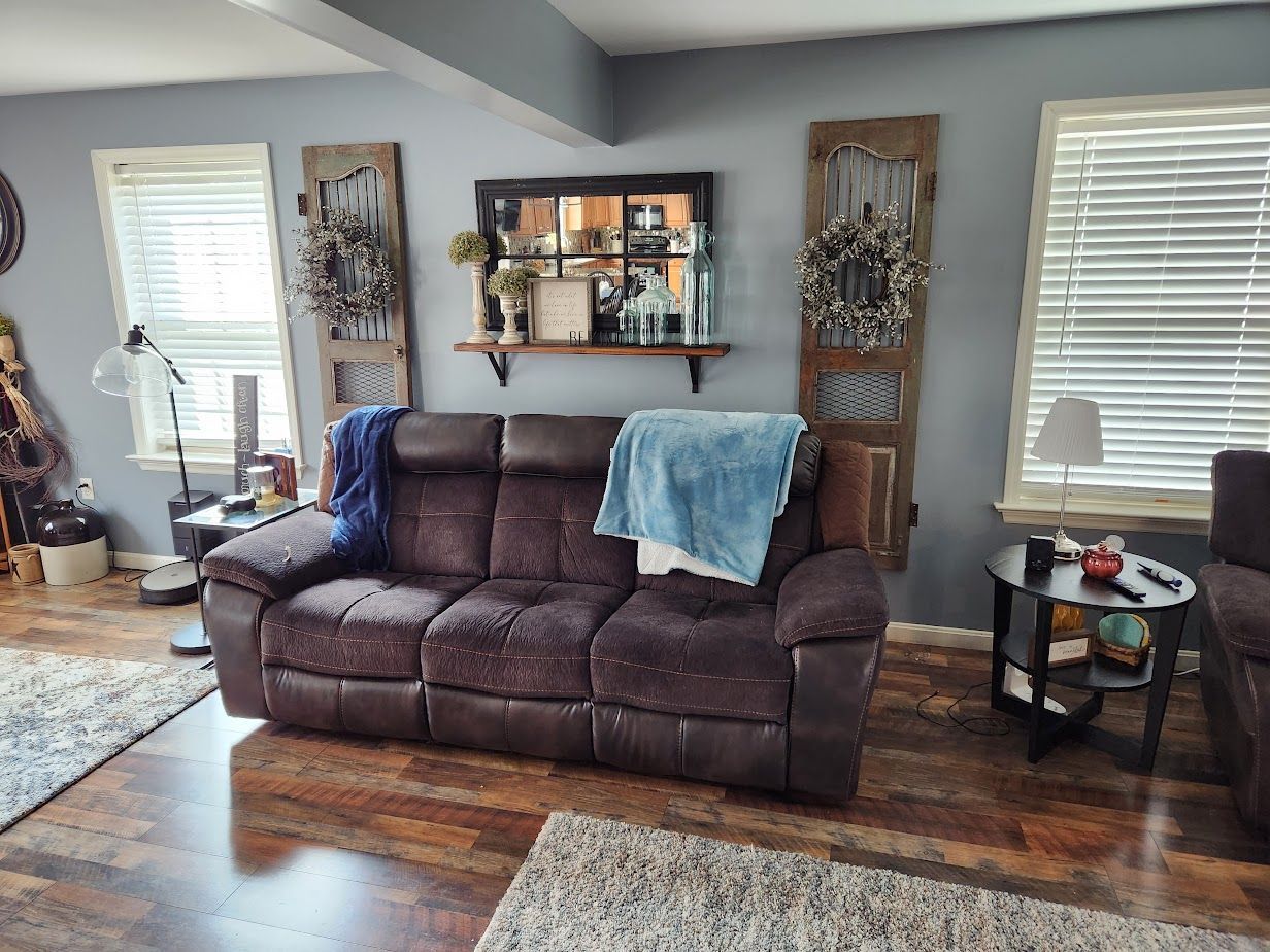 A living room with a brown couch , chair , table and mirror.