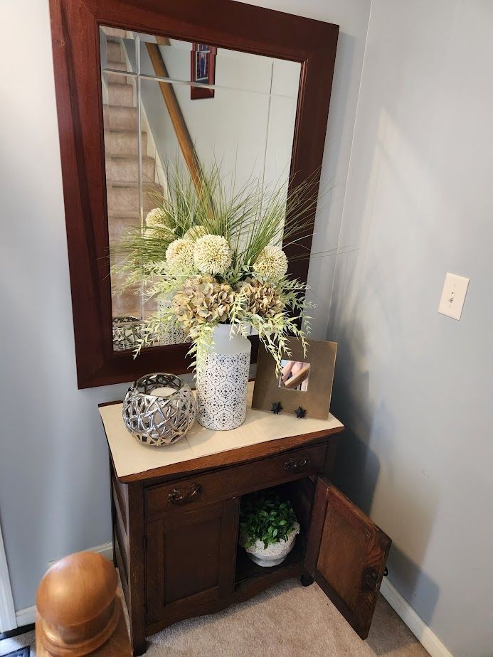 A mirror with a vase of flowers on top of it