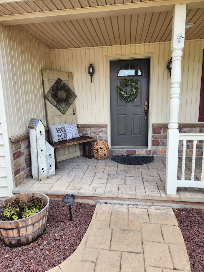 A porch with a bench and a wreath on the door.