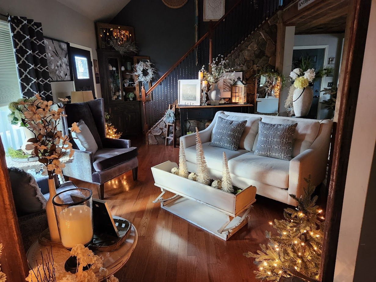 A living room with a couch , chair , coffee table and christmas decorations.