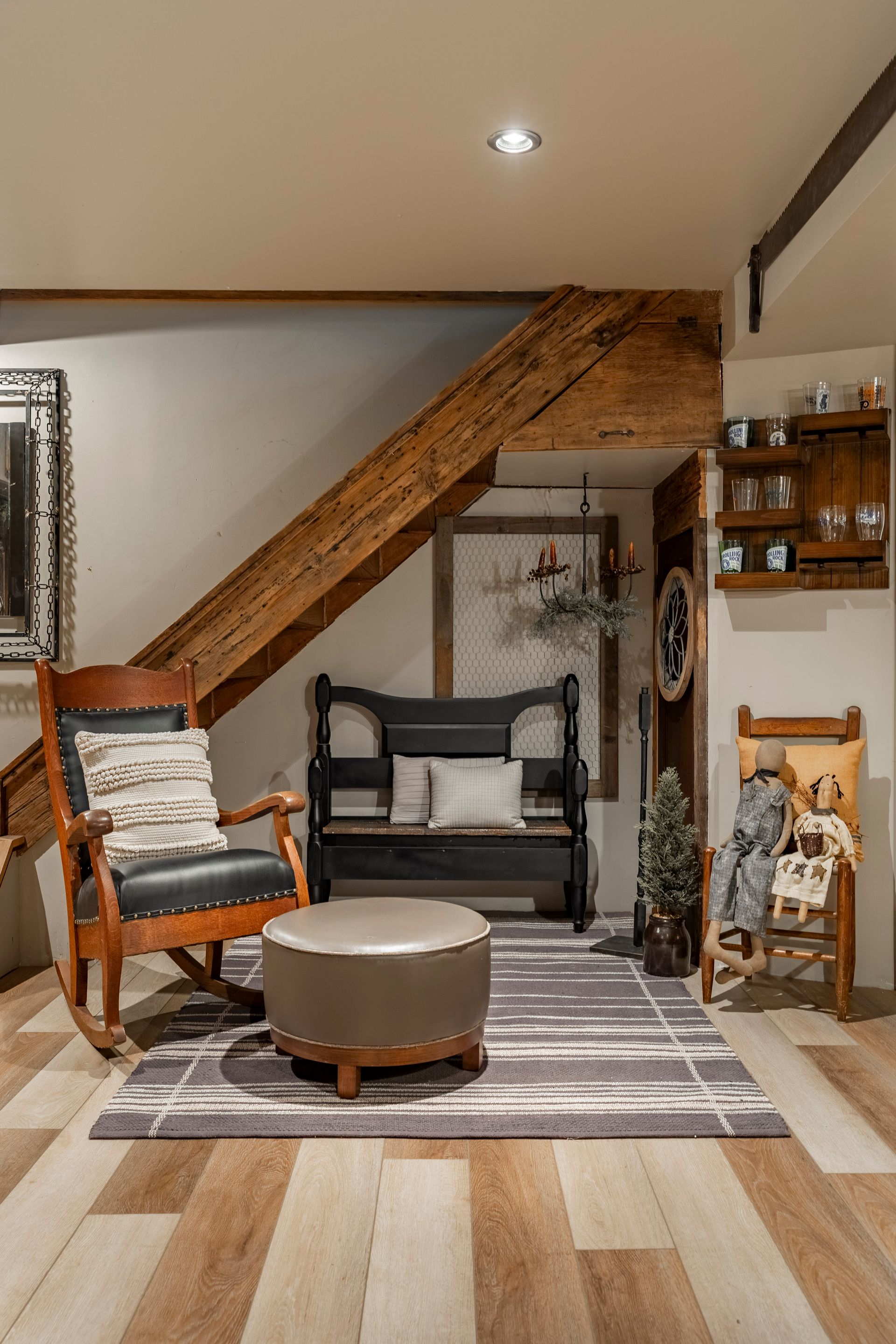 A living room with a rocking chair , ottoman , bench and stairs.
