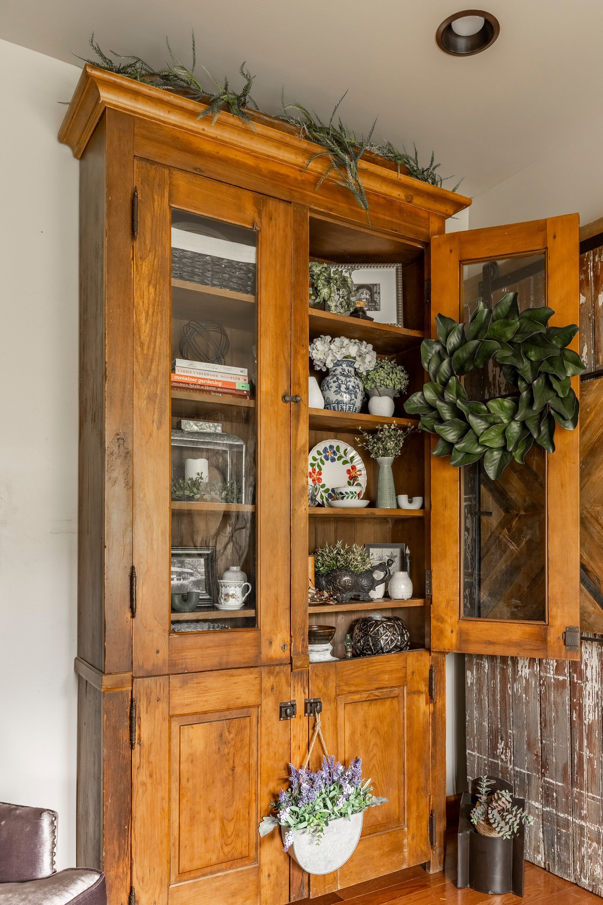 A wooden cabinet with glass doors and shelves in a living room.