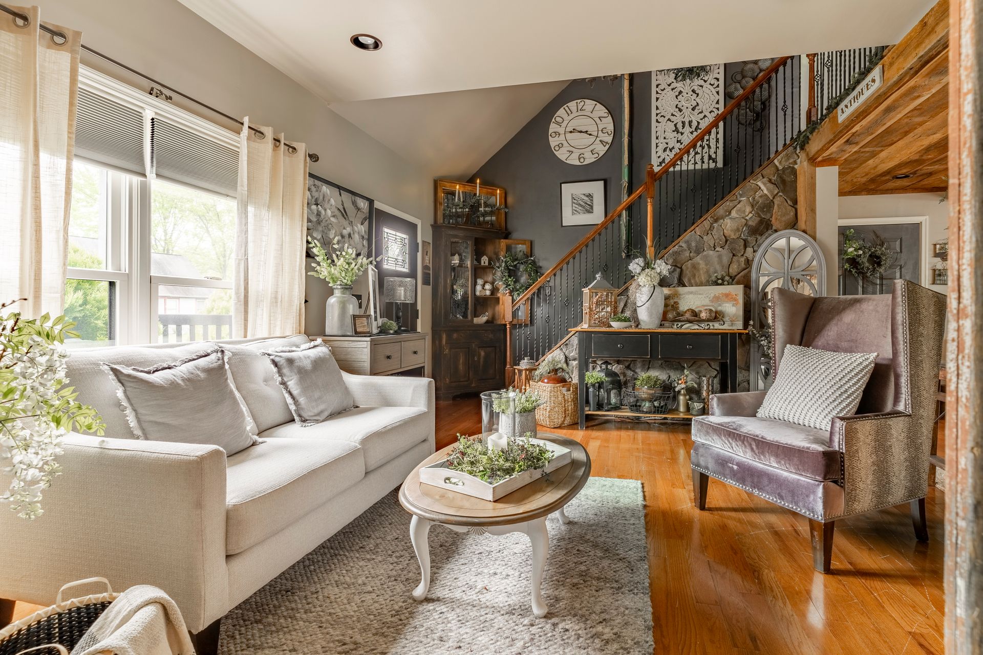 A living room with a couch , chair , coffee table and stairs.