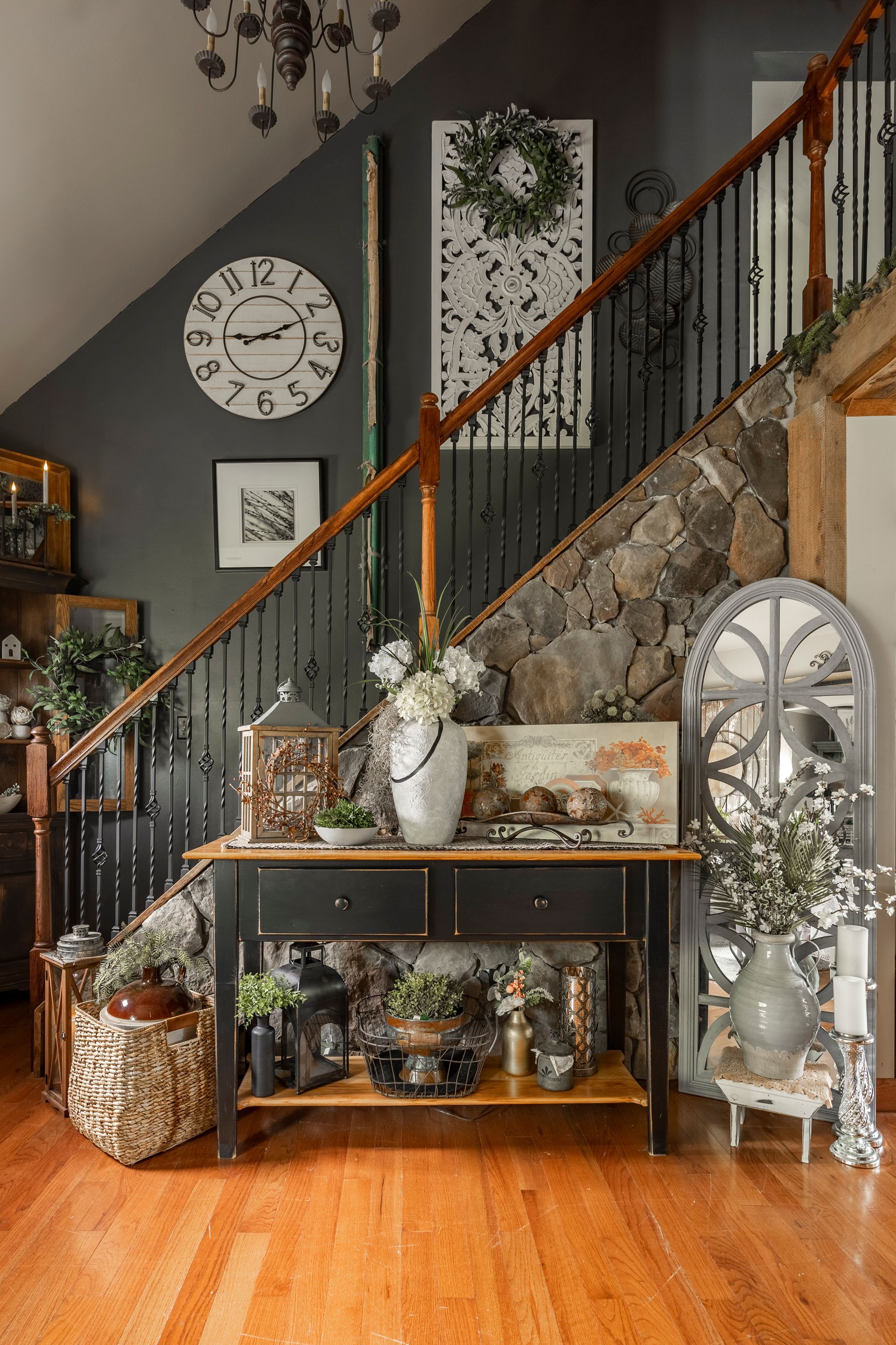 There is a clock on the wall above the stairs in the living room.