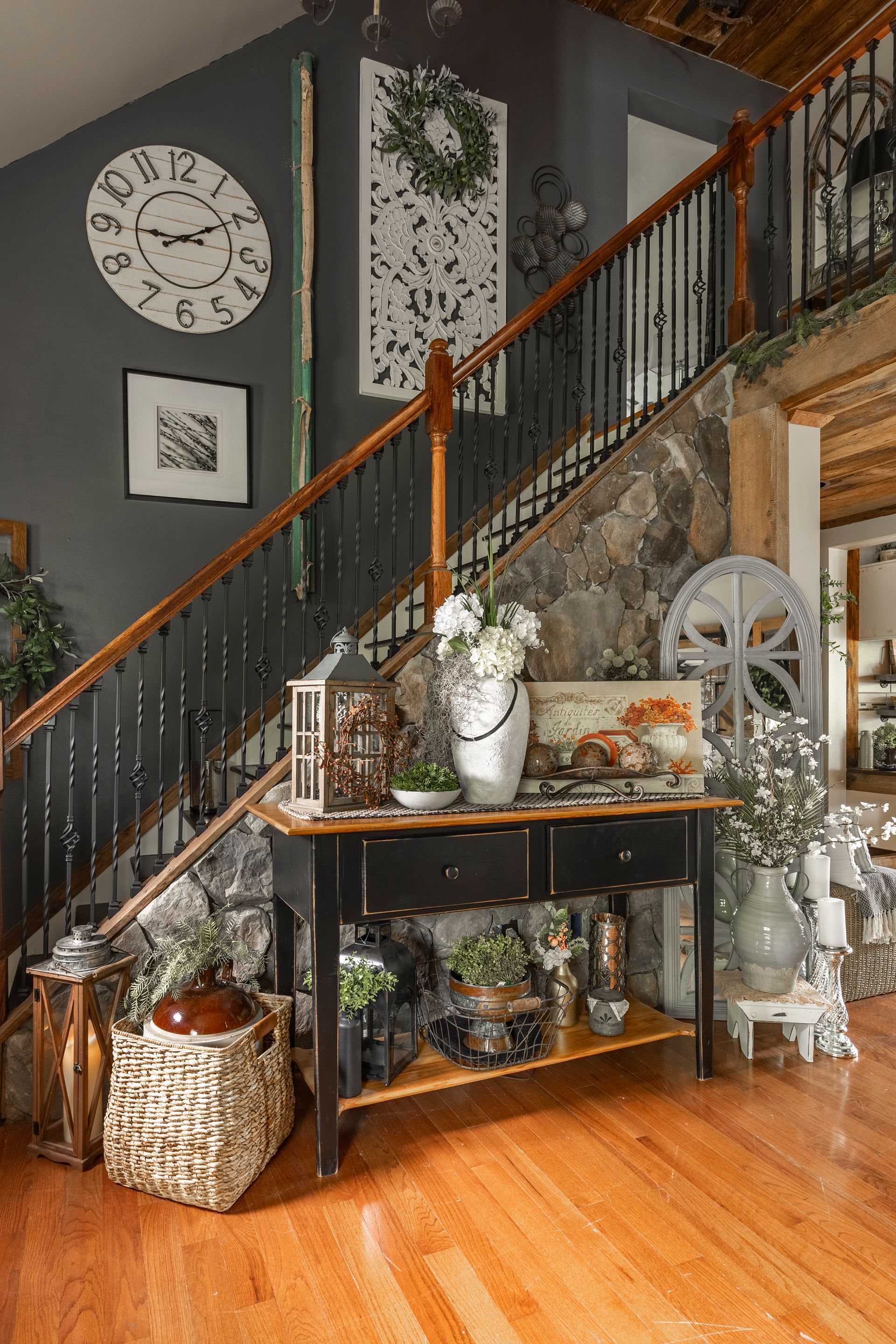 There is a clock on the wall above the stairs in the living room.
