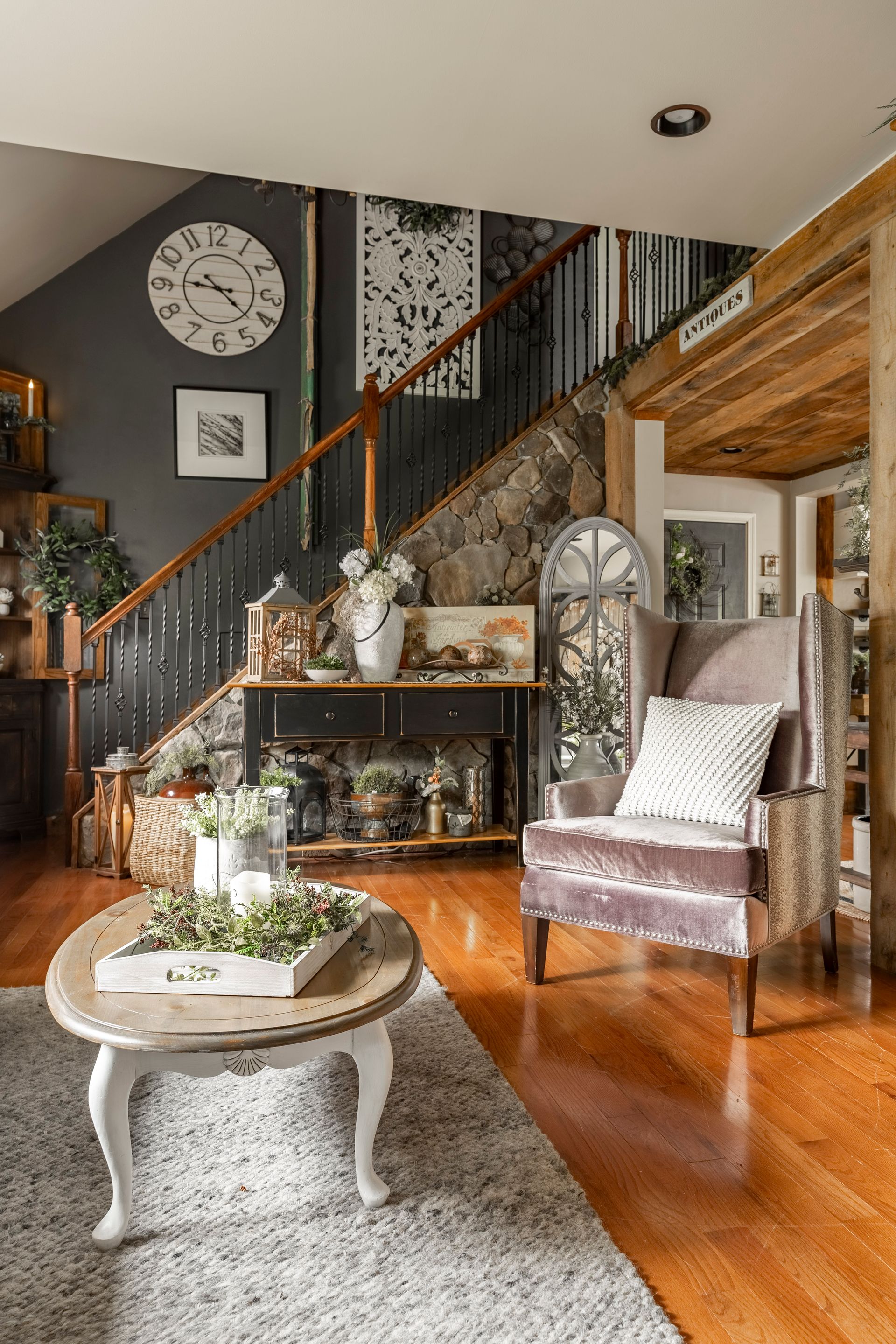 There is a clock on the wall above the stairs in the living room.