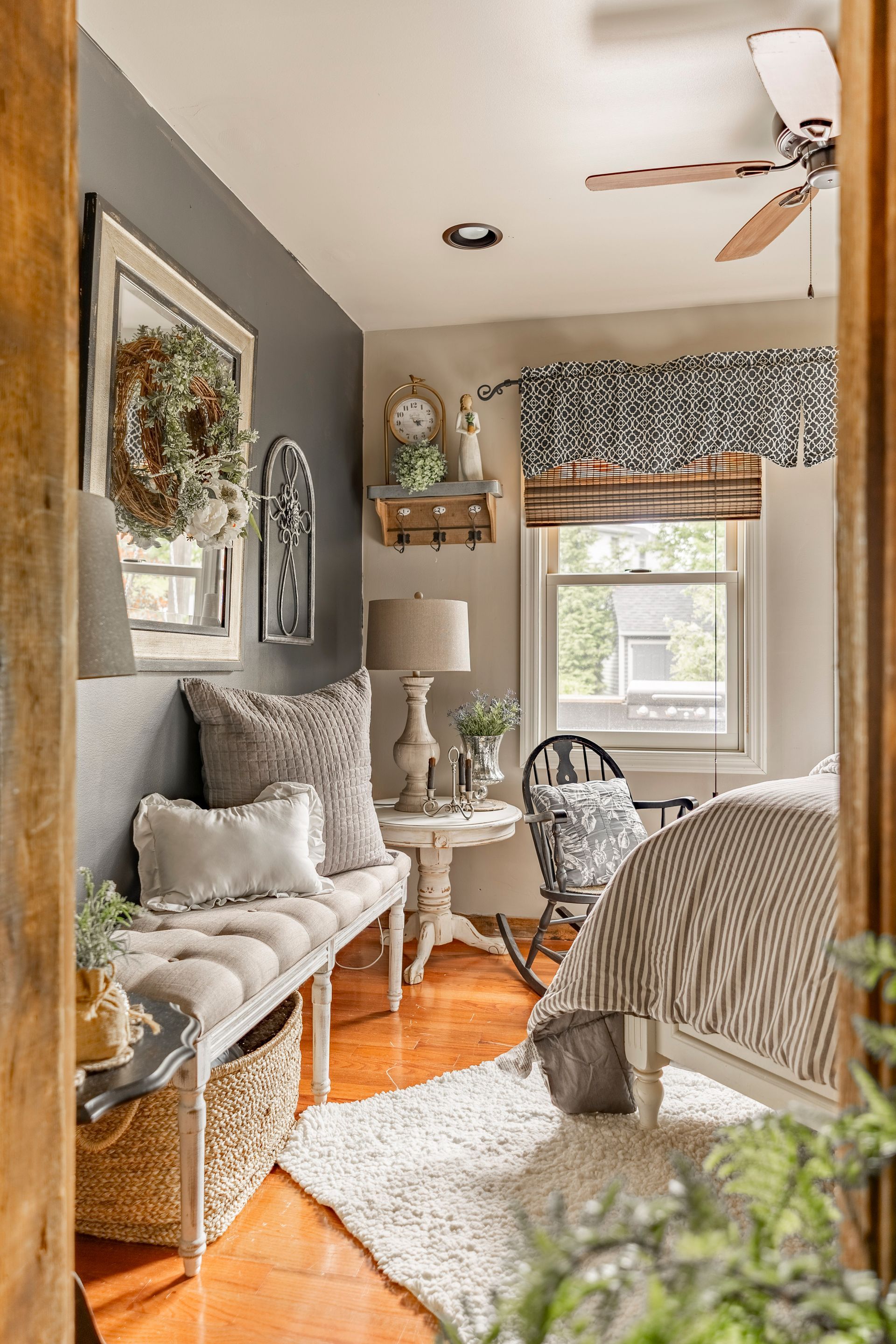 A bedroom with a bed , bench , table and ceiling fan.