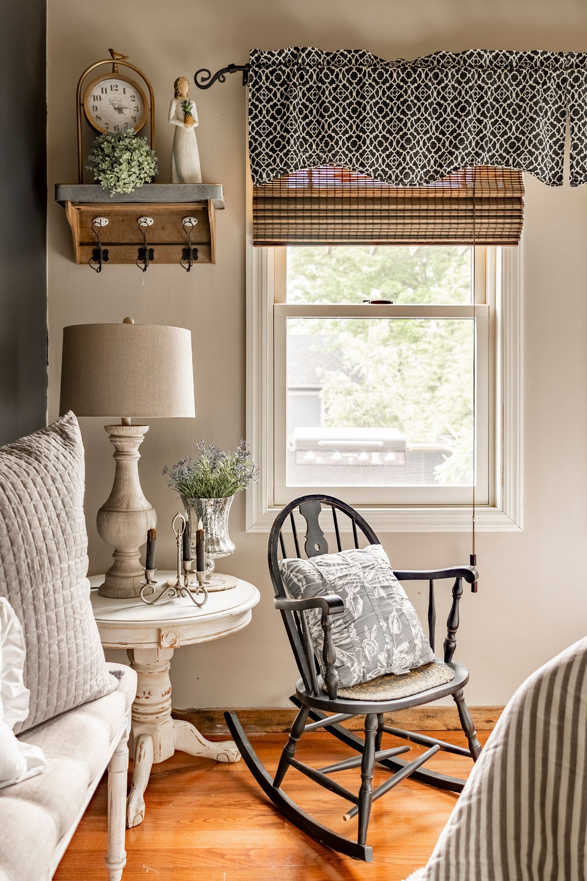 A living room with a rocking chair , table , lamp and clock.
