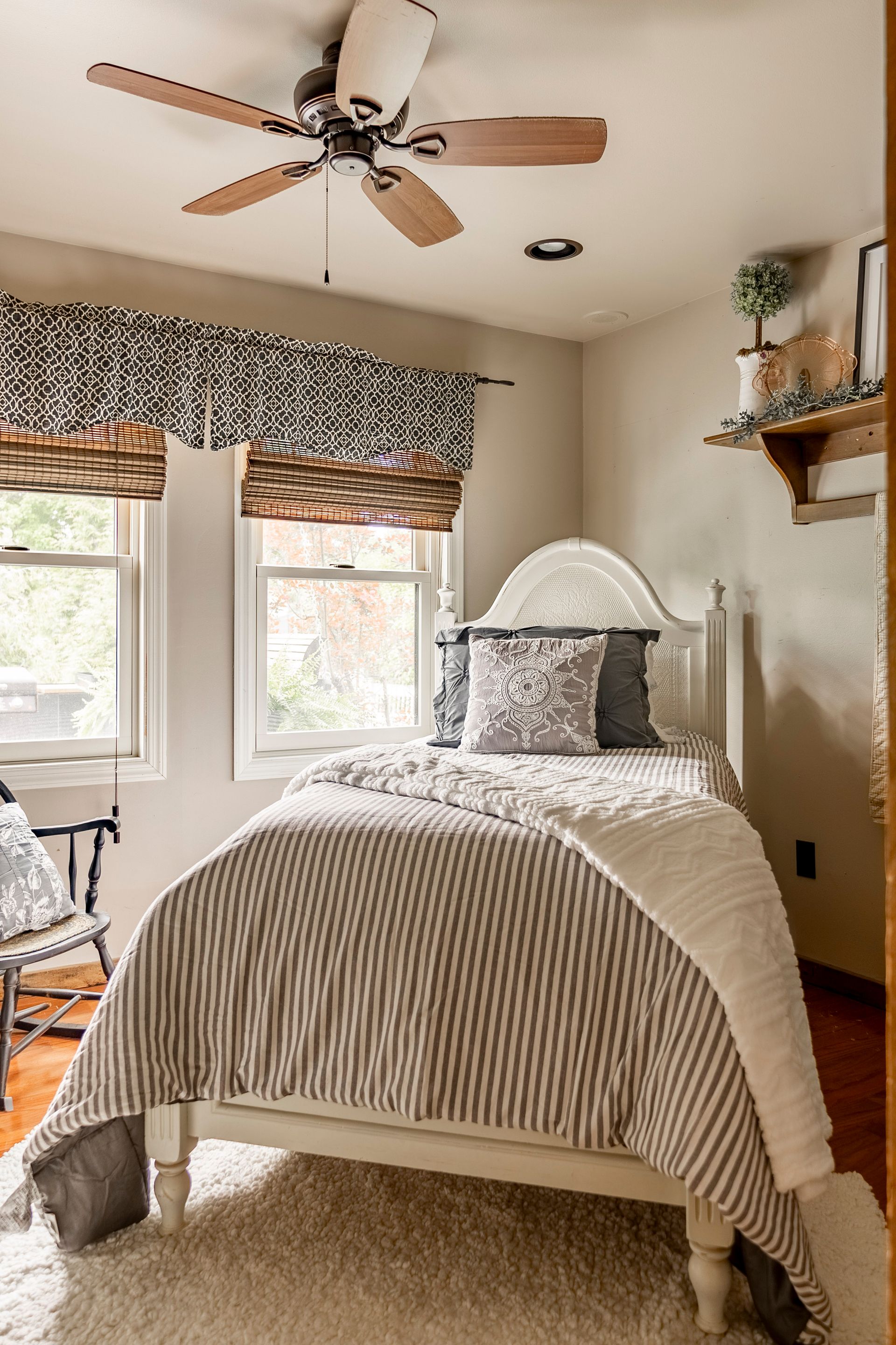 A bedroom with a single bed and a ceiling fan.