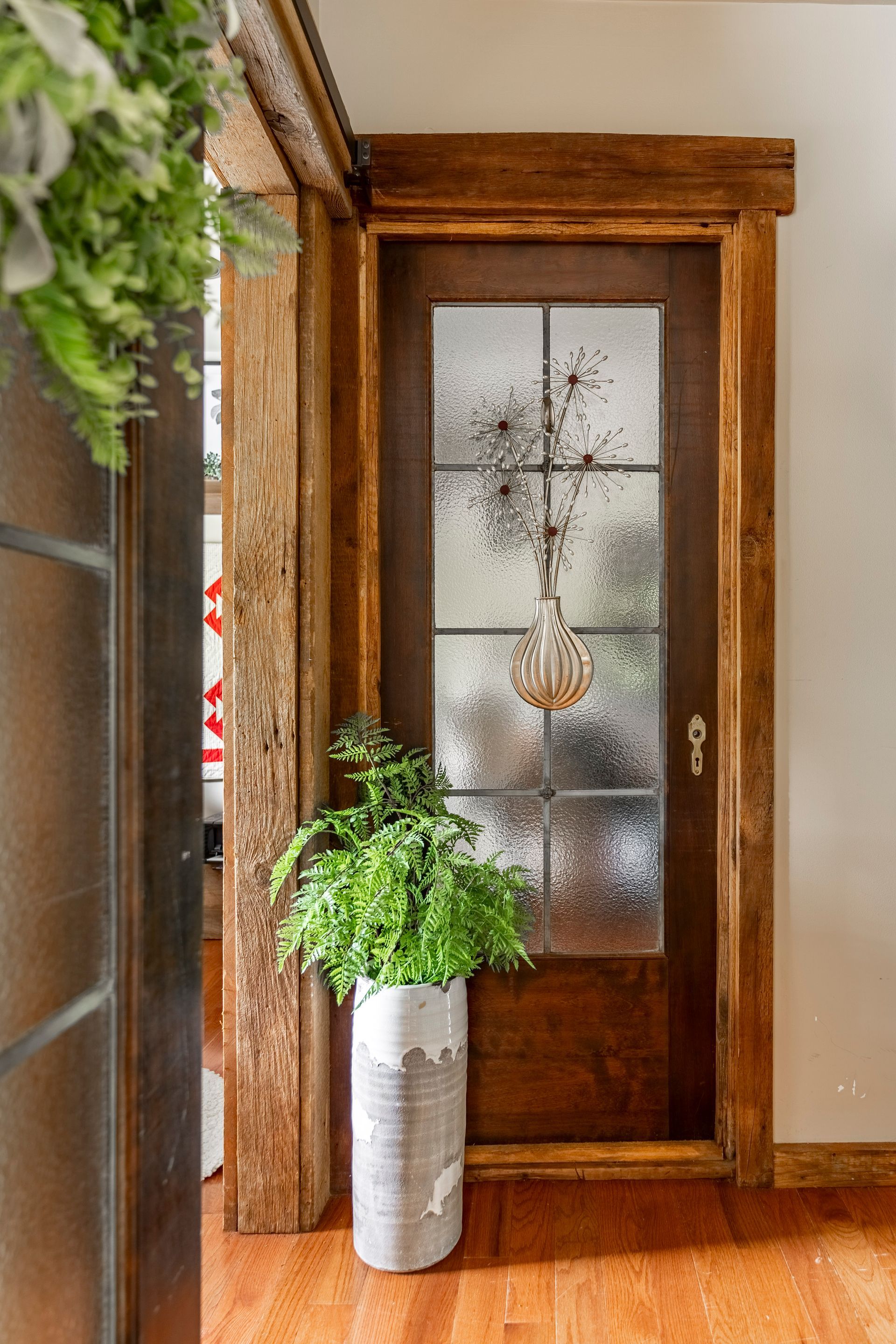 A potted plant is sitting in front of a wooden door with a stained glass window.