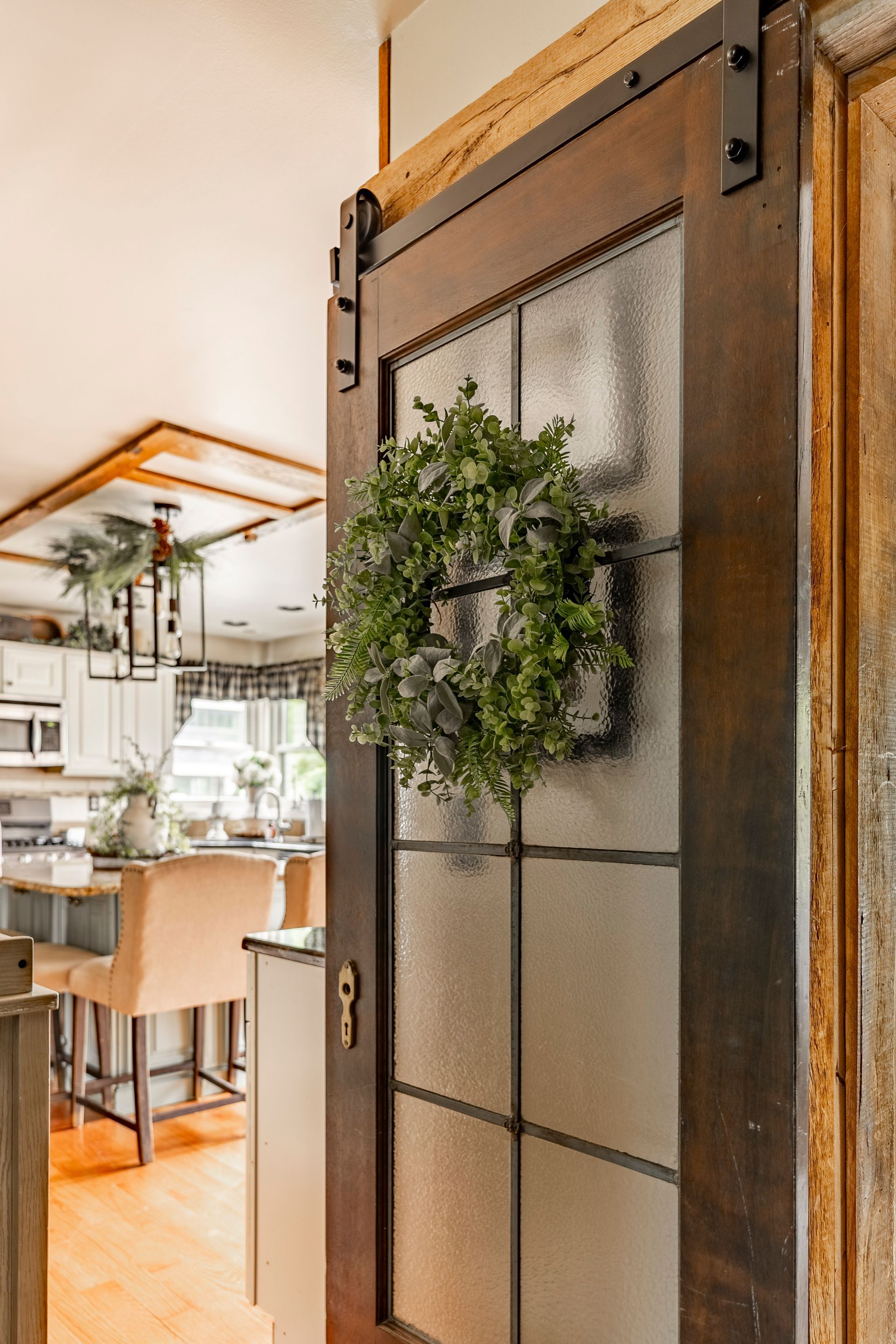 A sliding barn door with a wreath hanging on it in a kitchen.