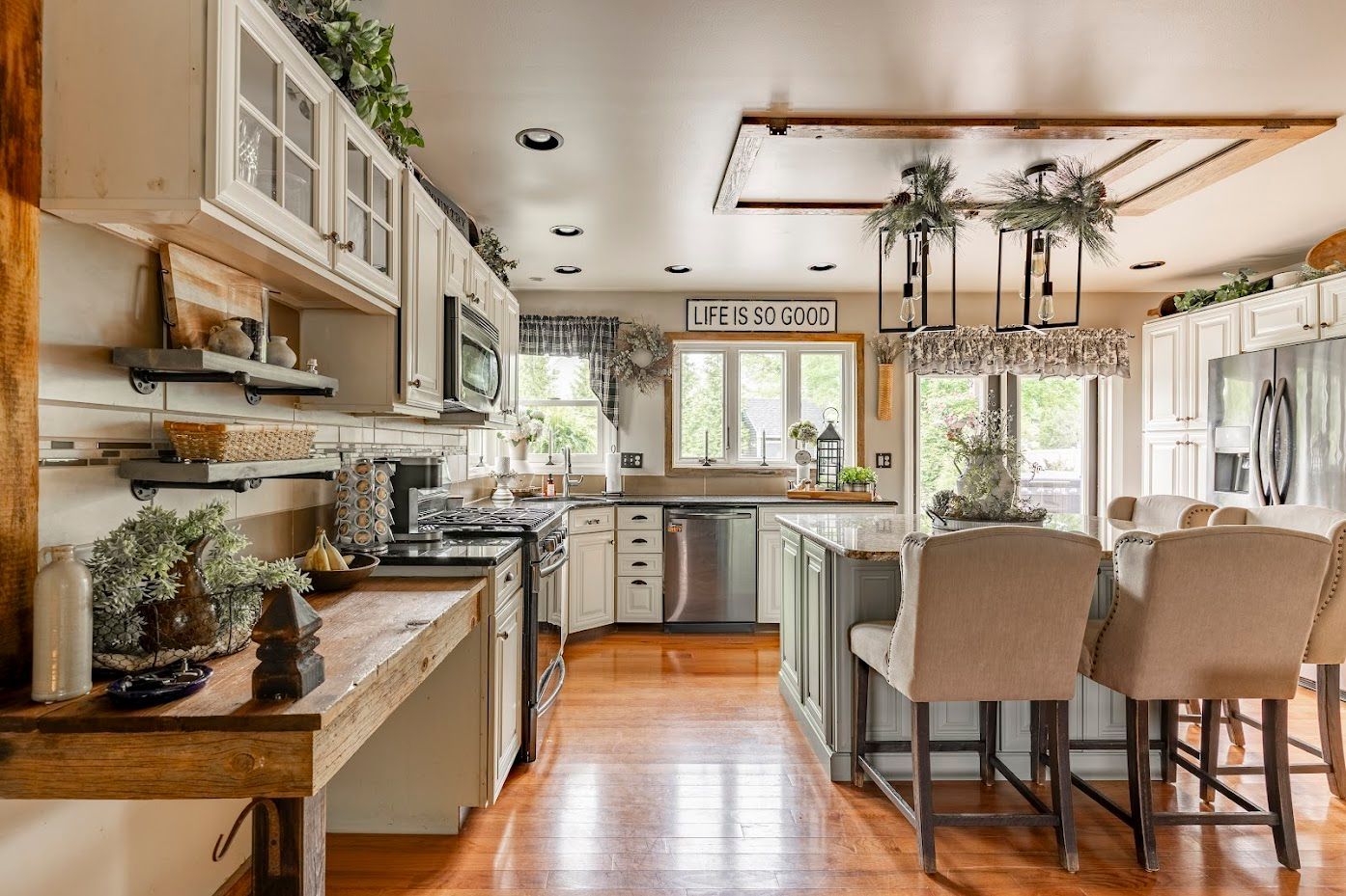 A kitchen with white cabinets , stainless steel appliances , hardwood floors and a large island.