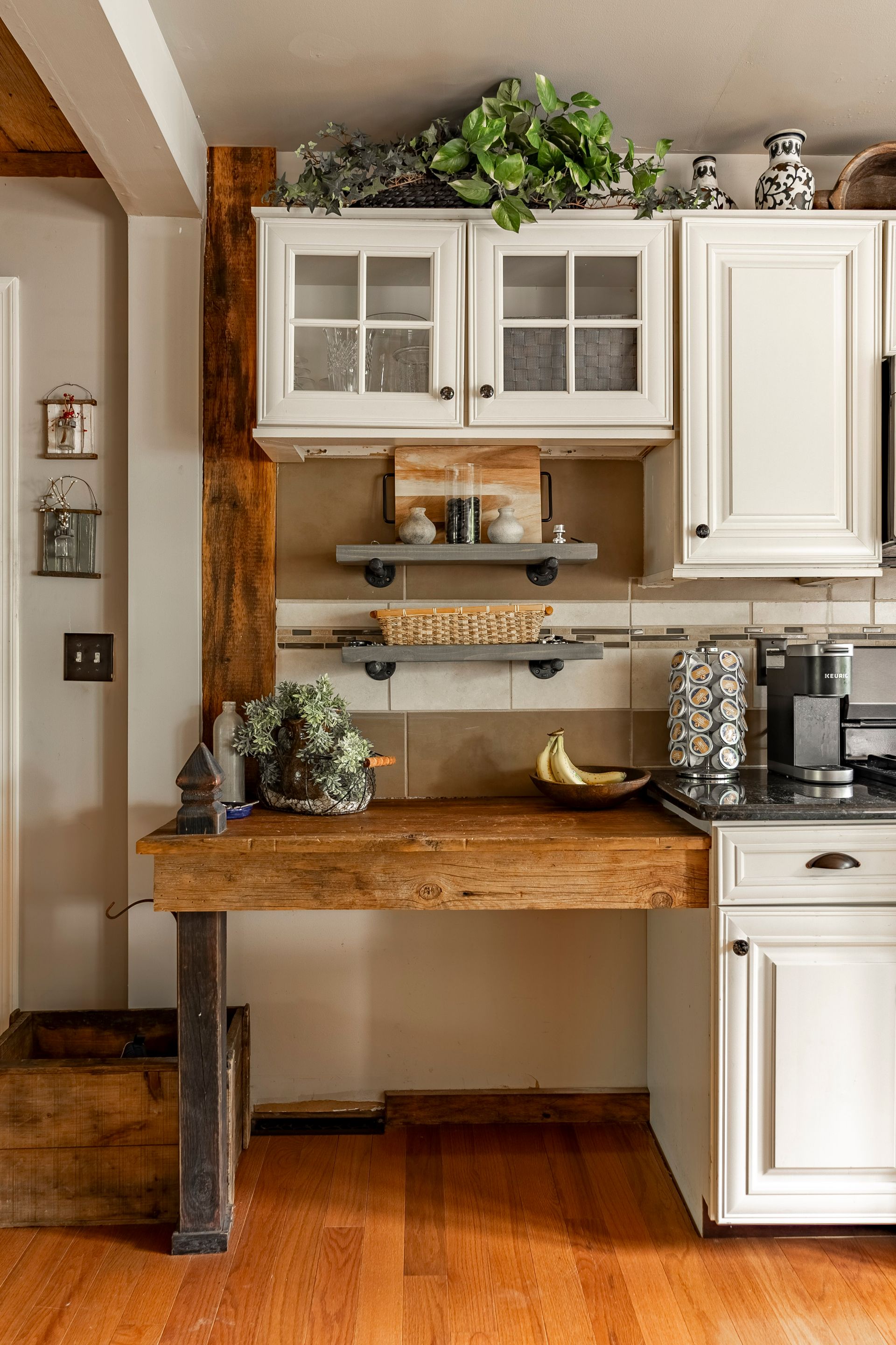 A kitchen with white cabinets and a wooden desk.