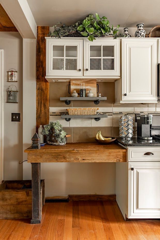 A kitchen with white cabinets and a wooden desk.