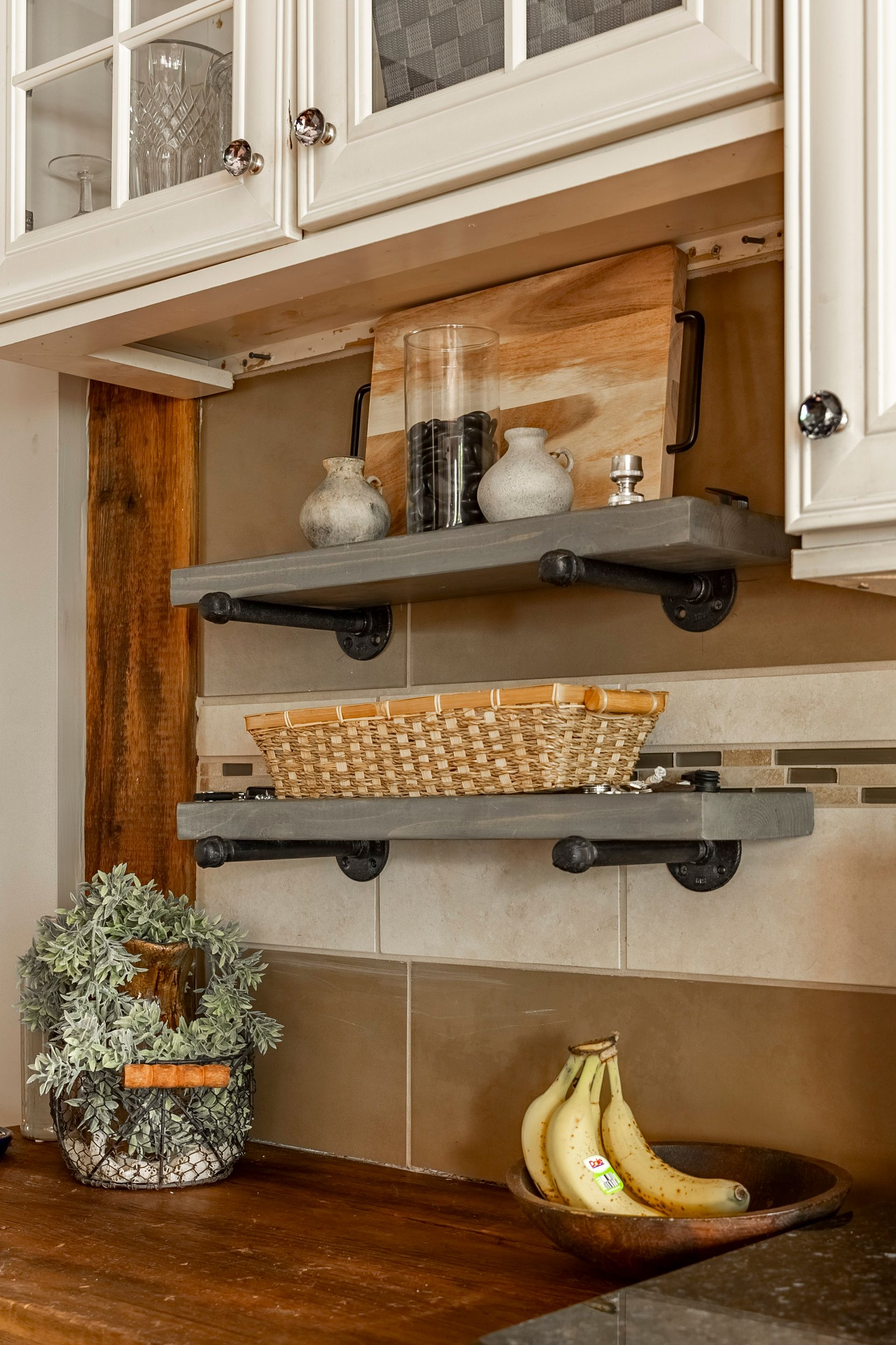 A kitchen with two shelves and a bowl of bananas on the counter.