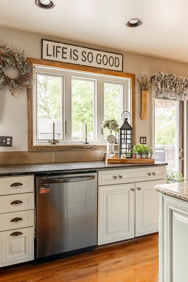 A kitchen with white cabinets , a stainless steel dishwasher , and a sign that says `` life is so good ''.