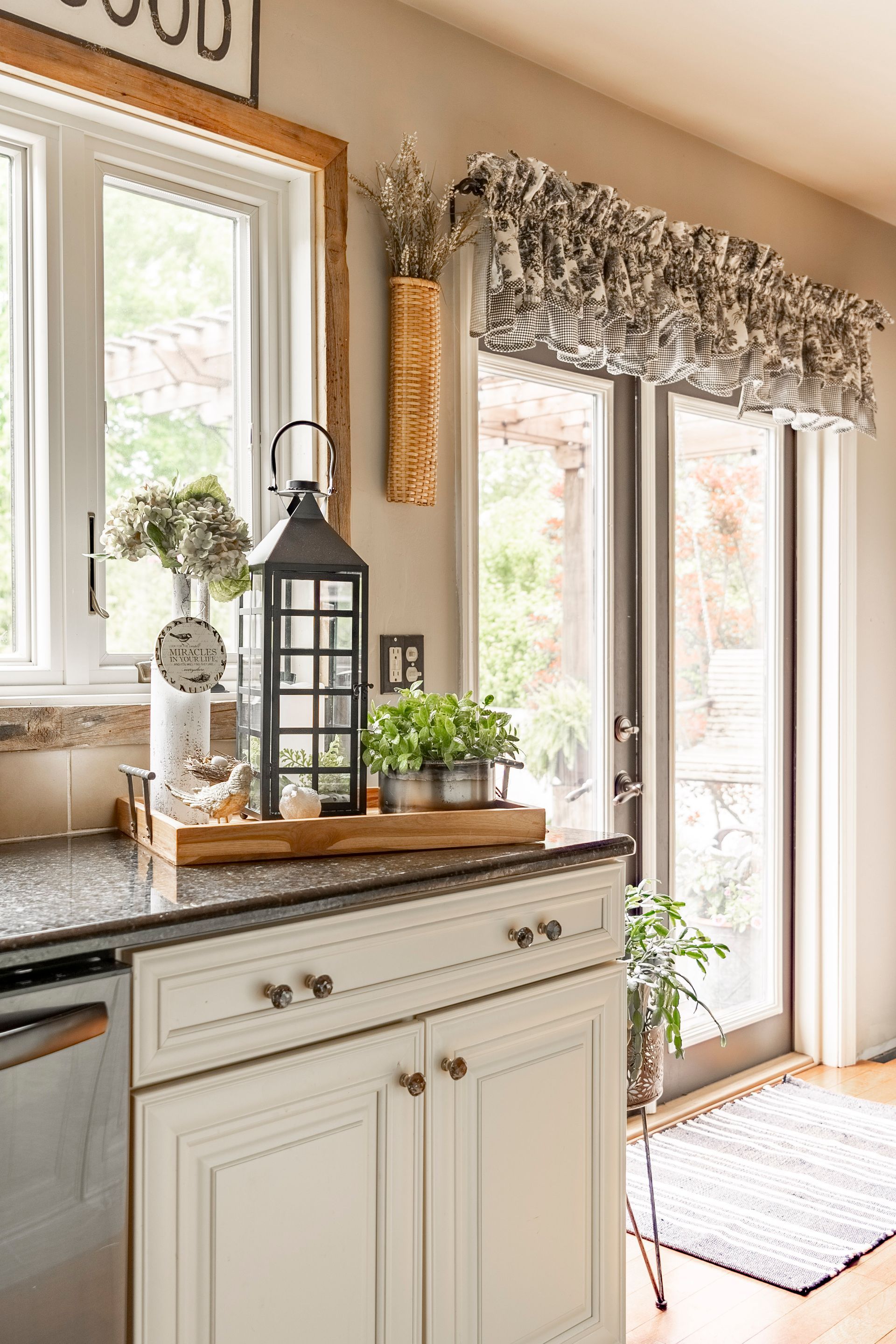 A kitchen with white cabinets , granite counter tops , stainless steel appliances and a lantern on the counter.
