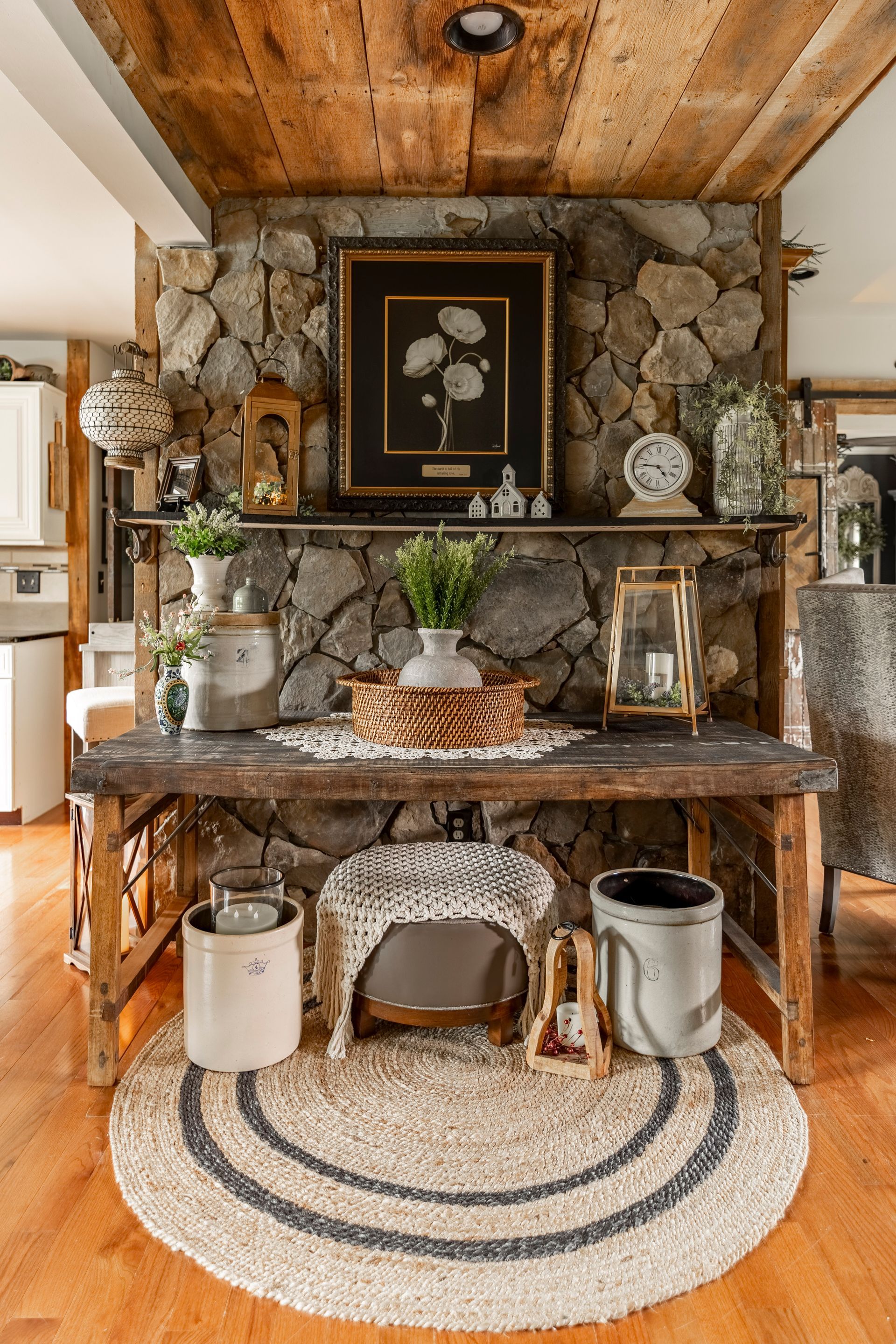 A living room with a stone fireplace and a wooden table.