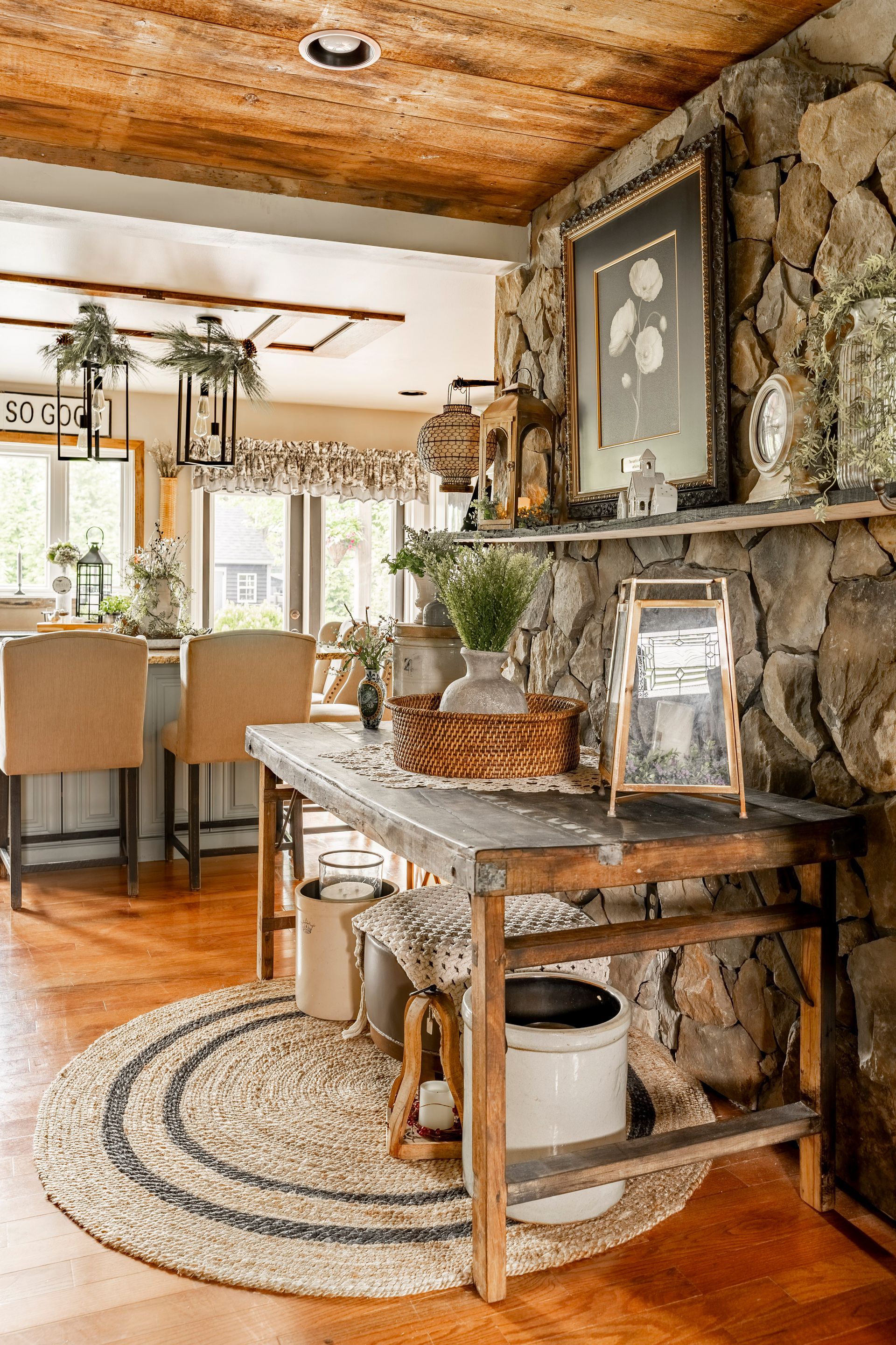 A living room with a wooden table and chairs and a stone fireplace.