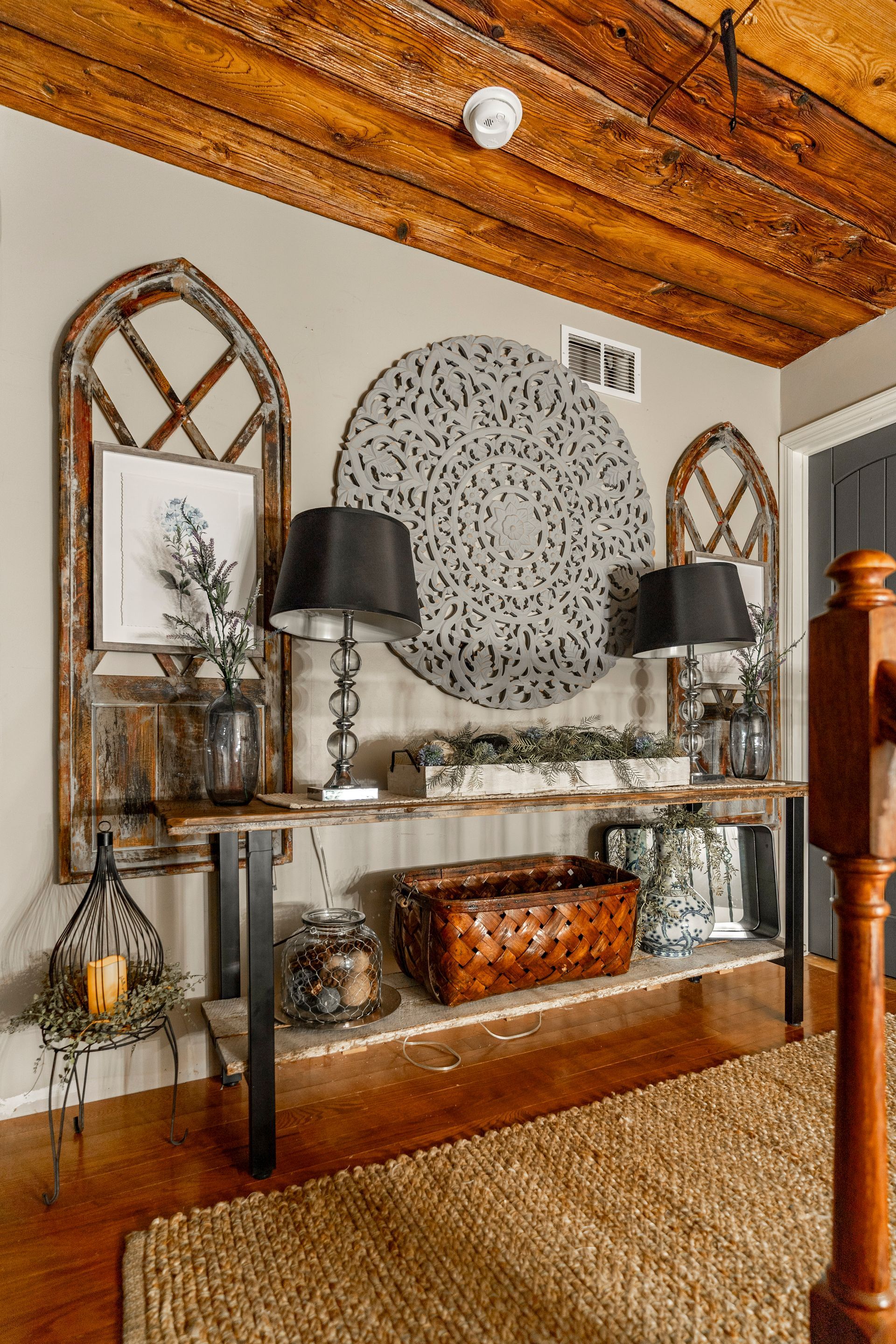 A living room with a wooden table , lamps , mirrors and a rug.