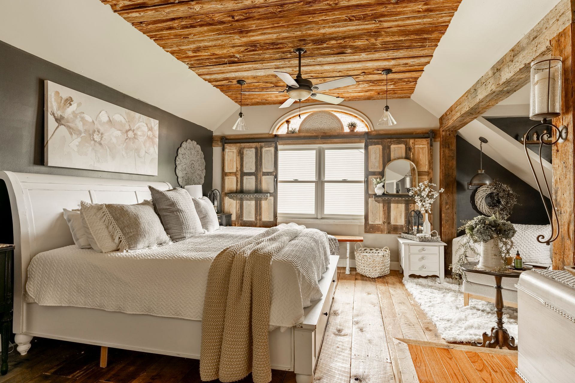 A bedroom with a bed , ceiling fan , and wooden floors.