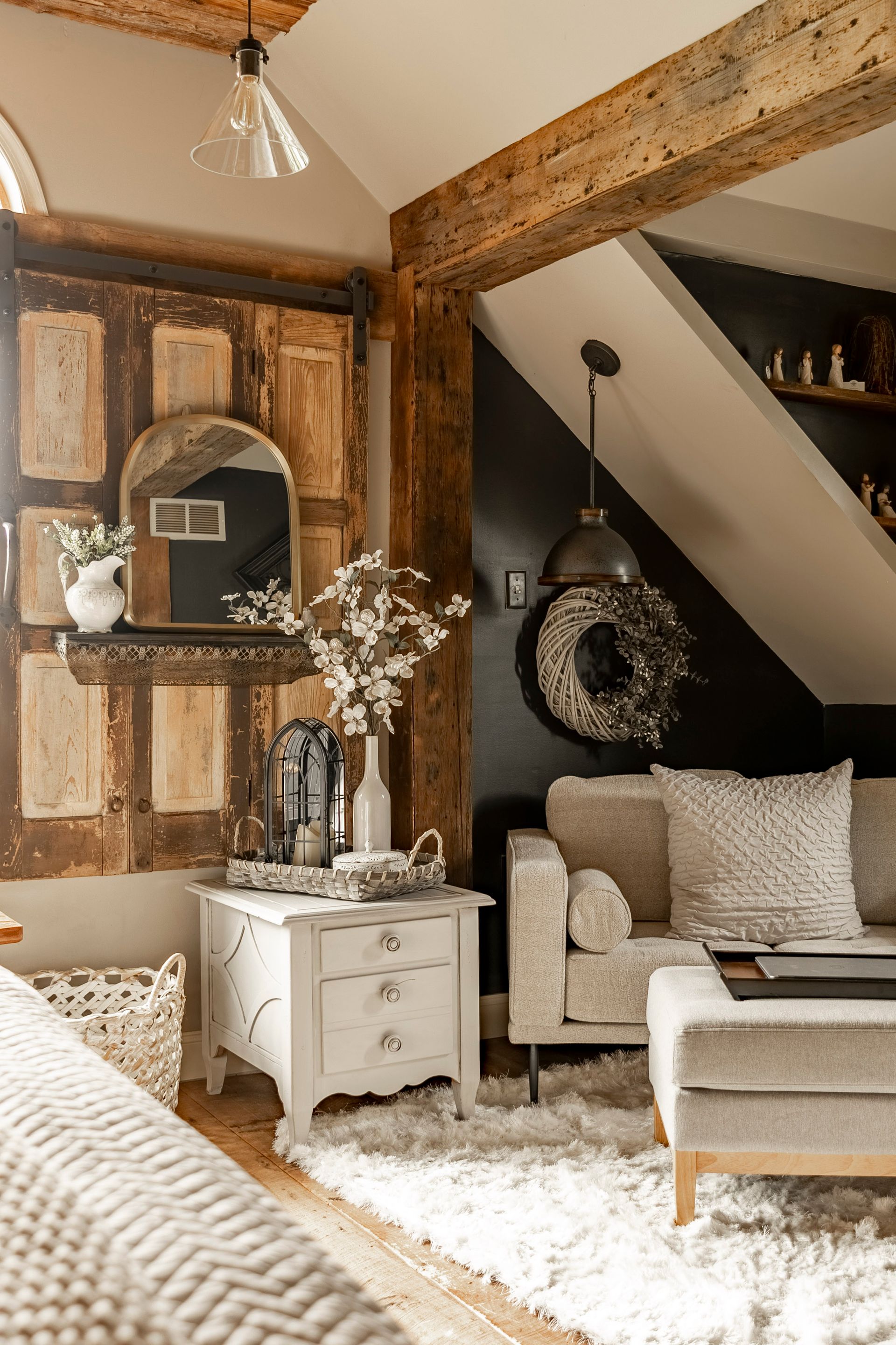 A living room with a couch , chair , nightstand , and mirror.