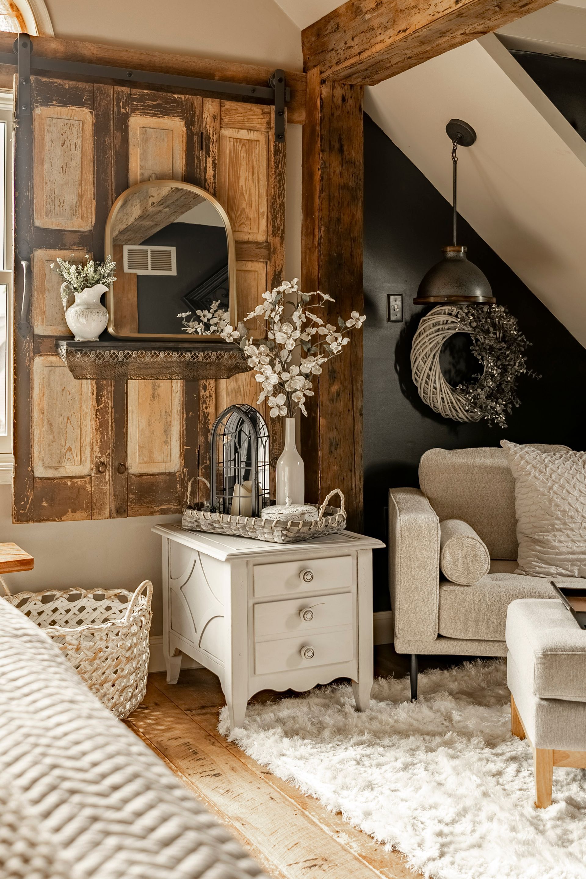 A living room with a couch , chair , nightstand , and mirror.