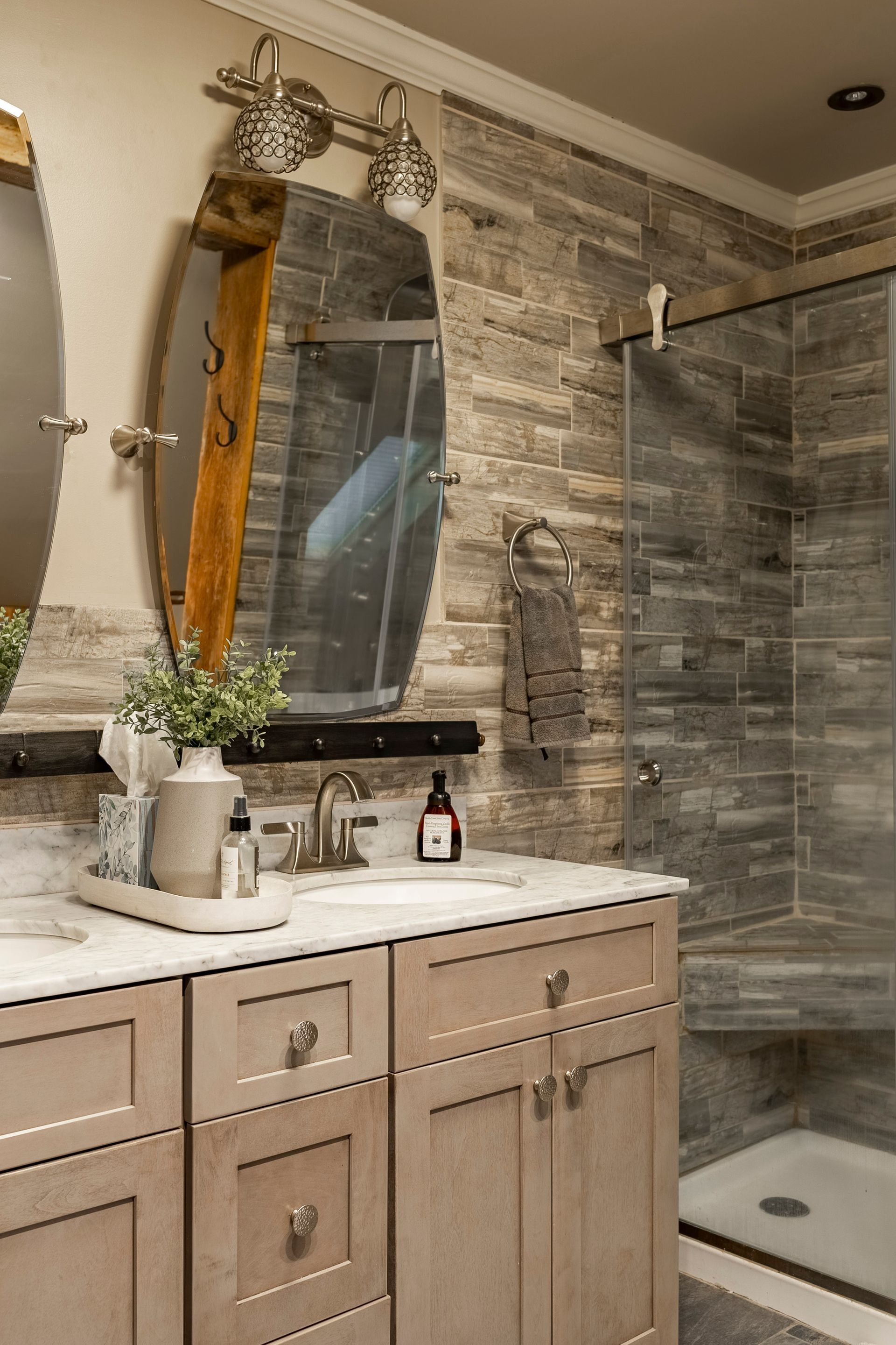 A bathroom with a sink , mirror , and walk in shower.