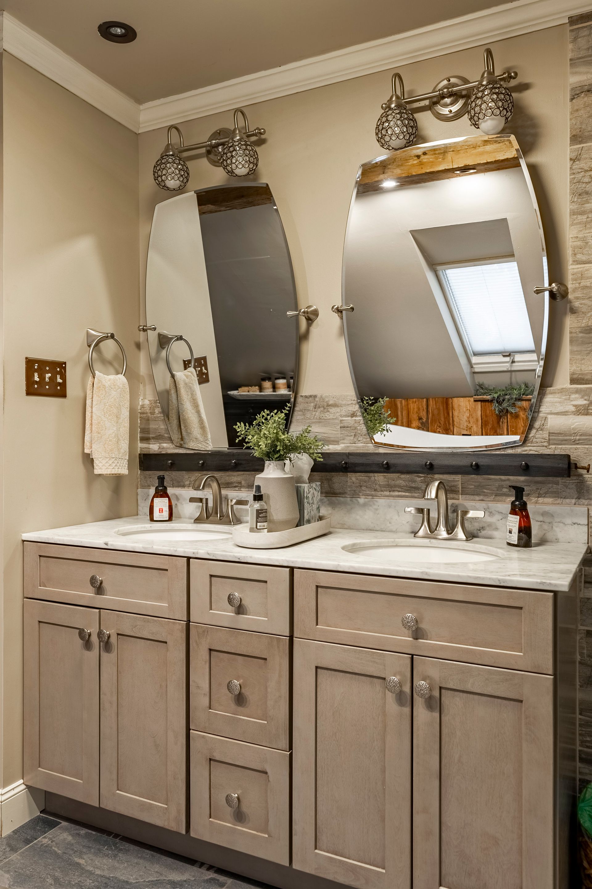 A bathroom with two sinks , two mirrors and a skylight.