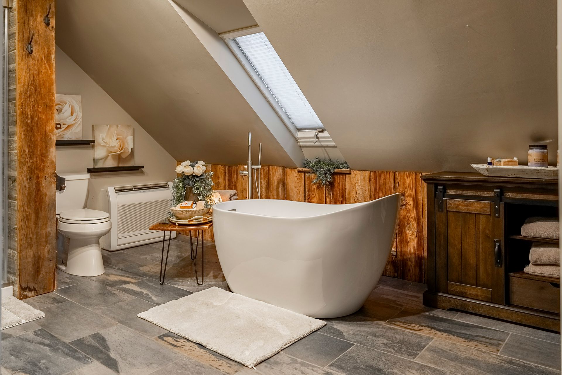 A bathroom with a bathtub , toilet , and skylight.