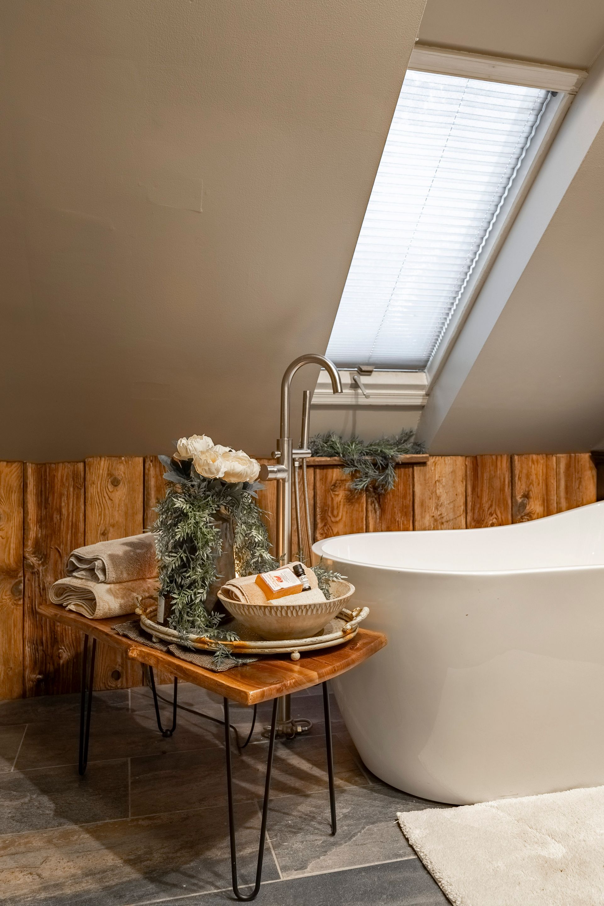 A bathroom with a bathtub and a table with flowers on it.