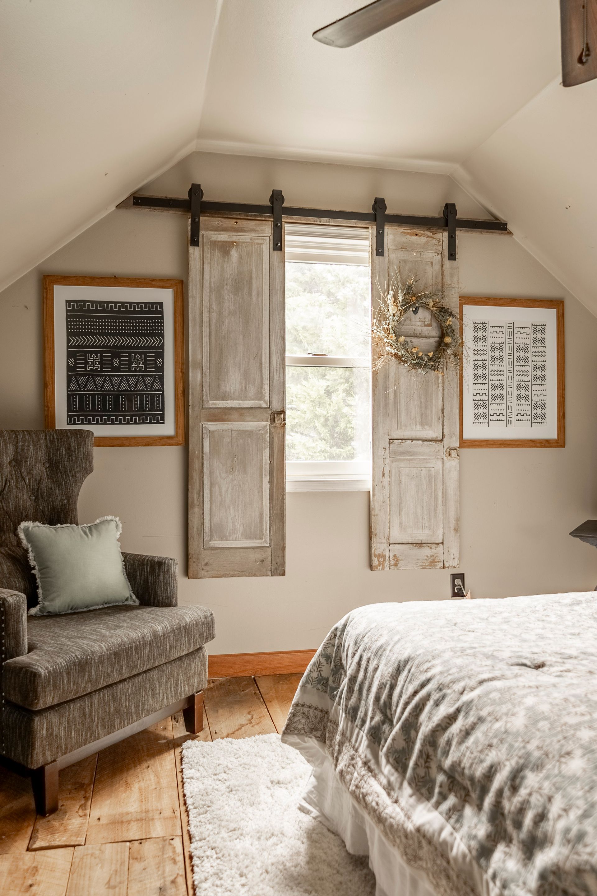 A bedroom with a bed , chair , and sliding barn doors.