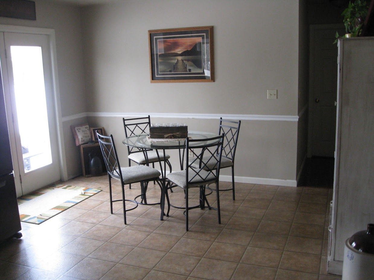 A dining room with a table and chairs and a picture on the wall