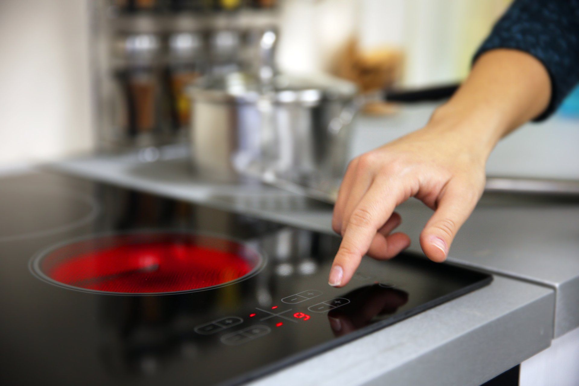 A person is pressing a button on an induction stove.