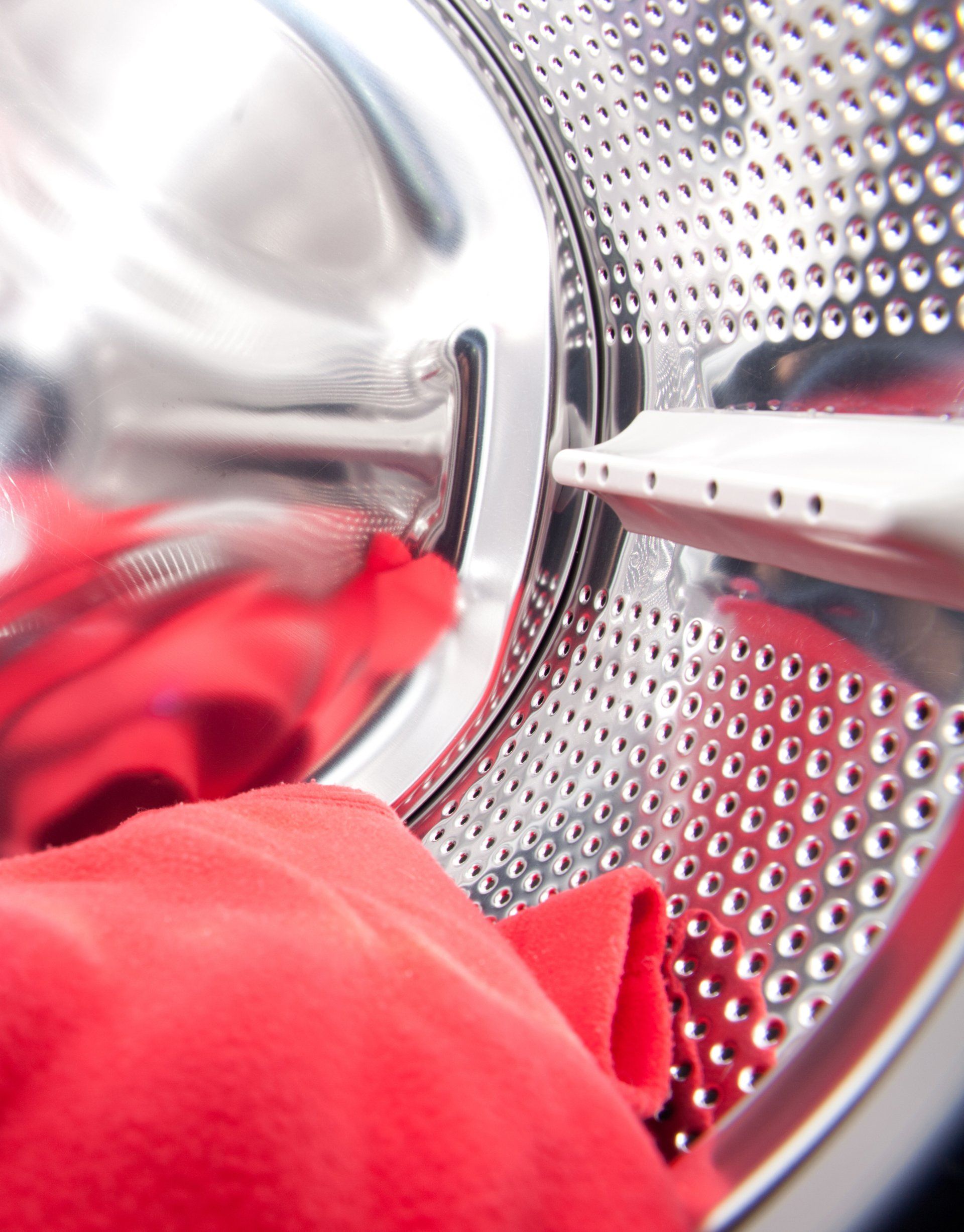 A close up of a washing machine with red clothes in it