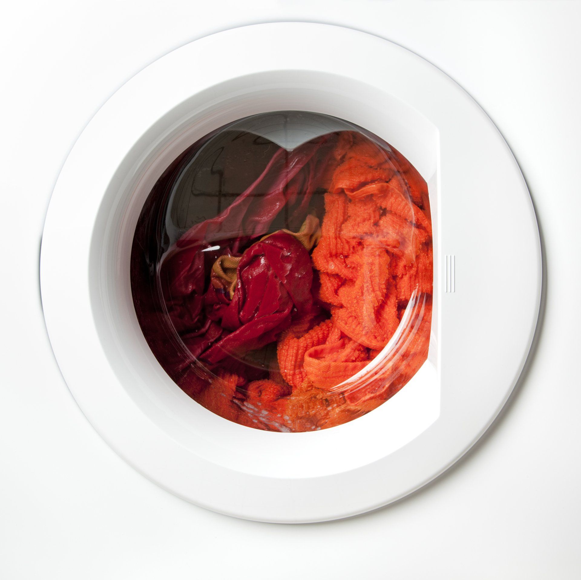 A washing machine filled with red and orange clothes