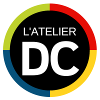 « Logo L'ATELIER DC : Cercle noir avec les lettres blanches « DC » et « L'ATELIER ». L'anneau extérieur comporte des sections rouges, jaunes, vertes et bleues. »