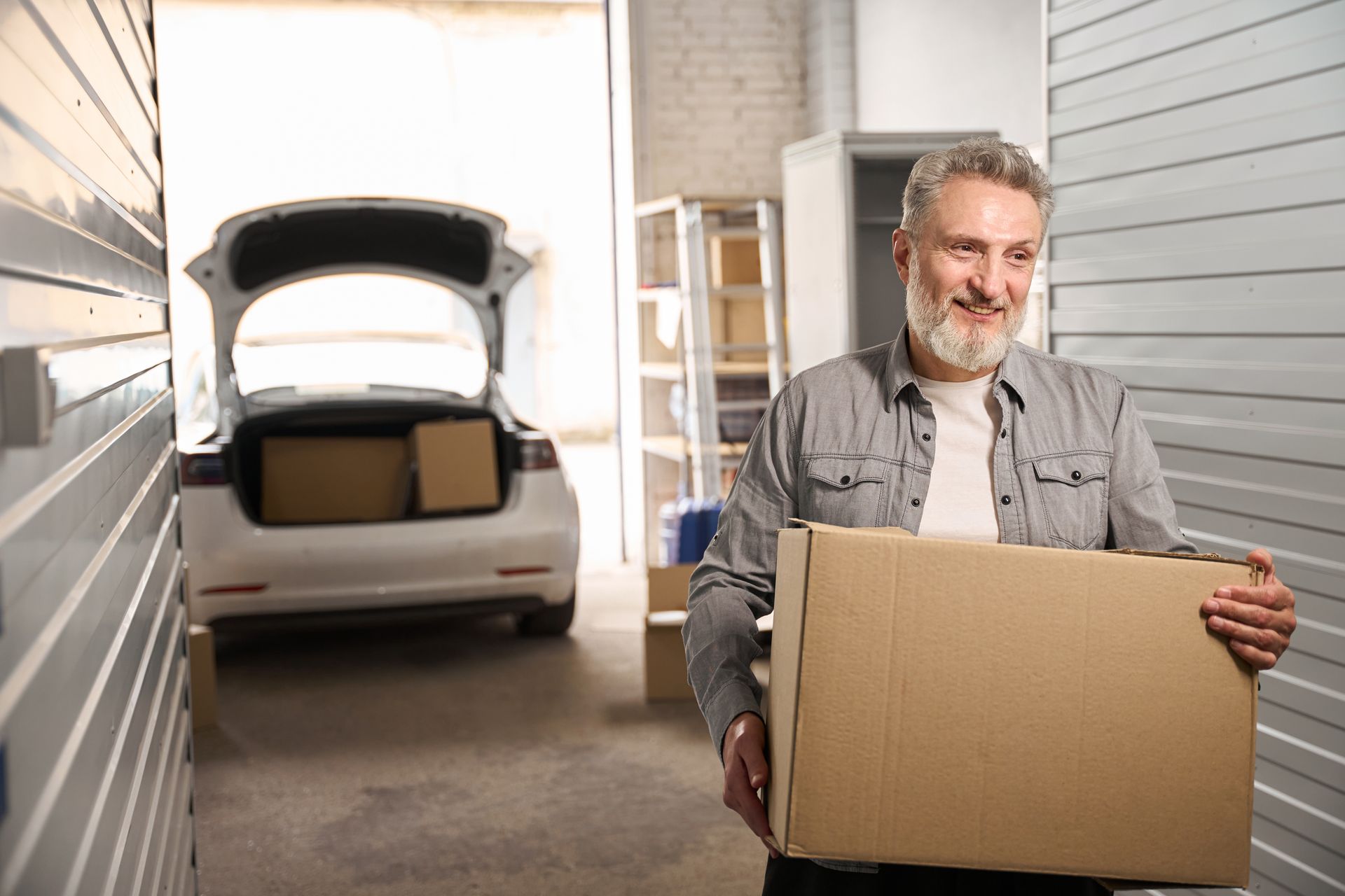 Smiling client in storage unit holding carton box. Smiling client in storage unit holding carton box.