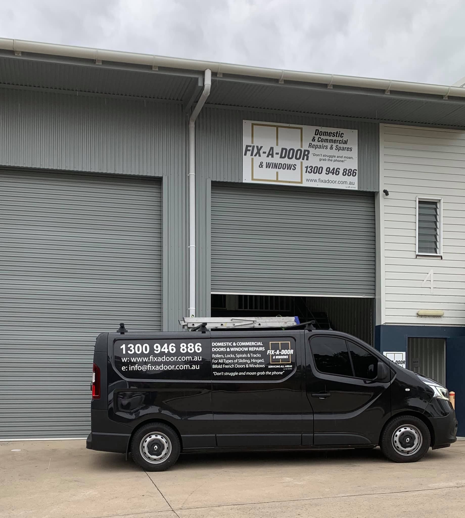 Black Van With Logo Parked in Front of a Building With a Roll-up Door — Fix-A-Door in Morisset, NSW