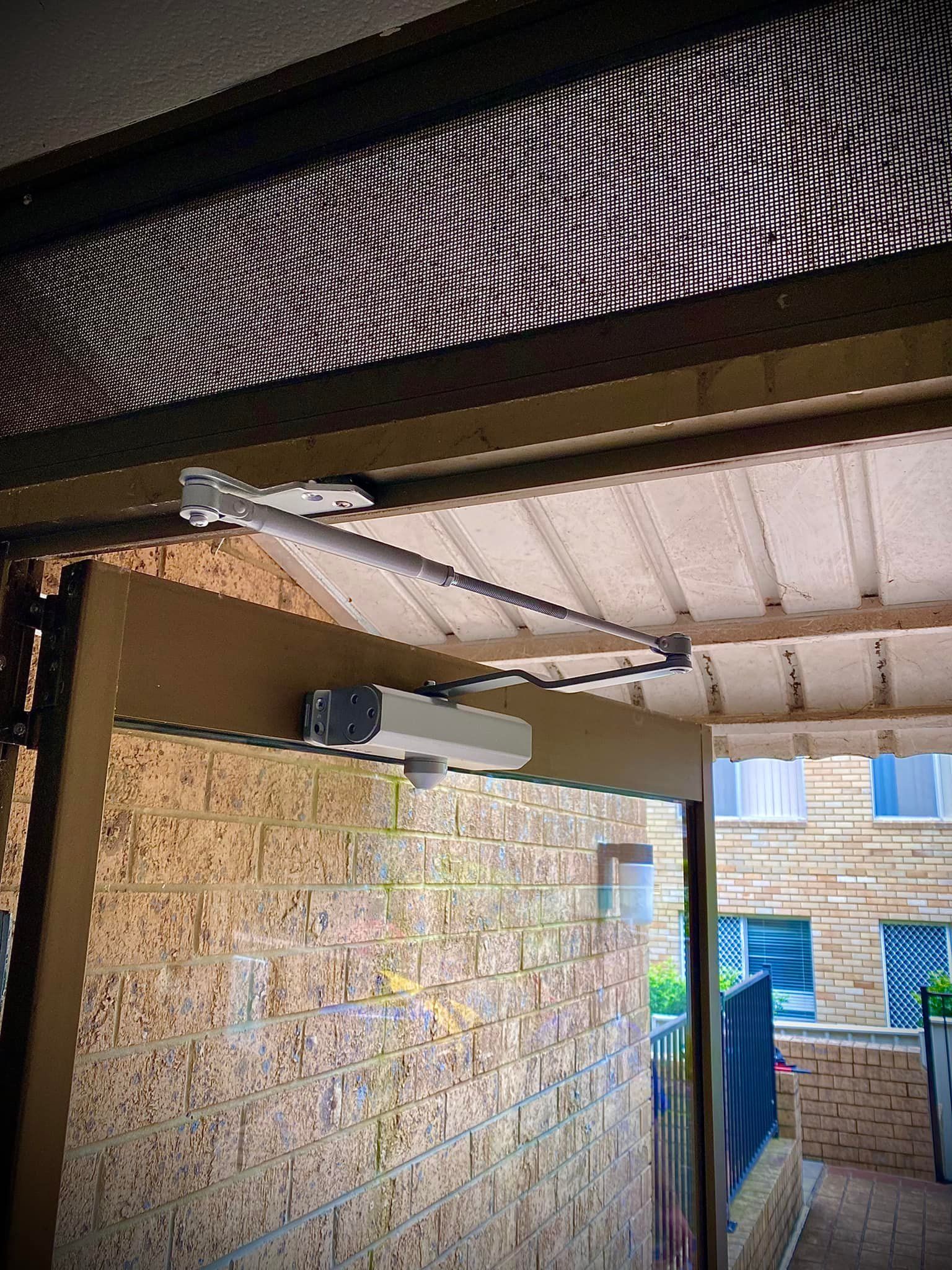 An Awning Support System Above a Brick Wall. The Metal Frame Extends Outward — Fix-A-Door in Lake Macquarie, NSW