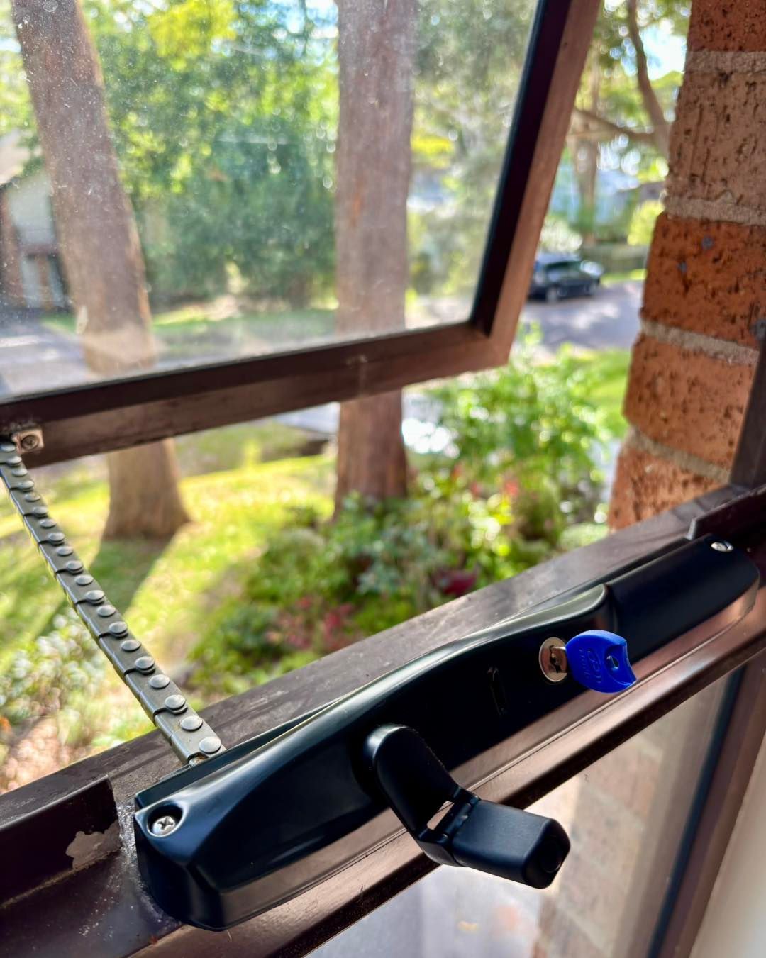 Open Awning Window With Black Handle, Blue Key, and Metal Arm — Fix-A-Door in Lake Macquarie, NSW