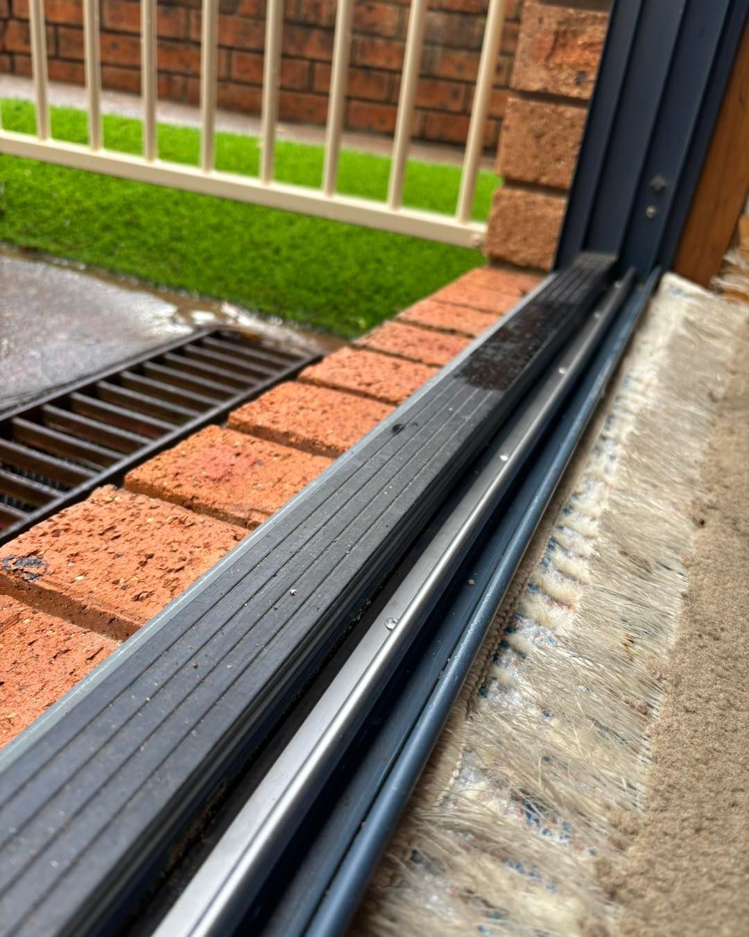 Sliding Door Track With Dark Rubber Seal, Brick, and Concrete. Rain Near a Gutter — Fix-A-Door in Morisset, NSW