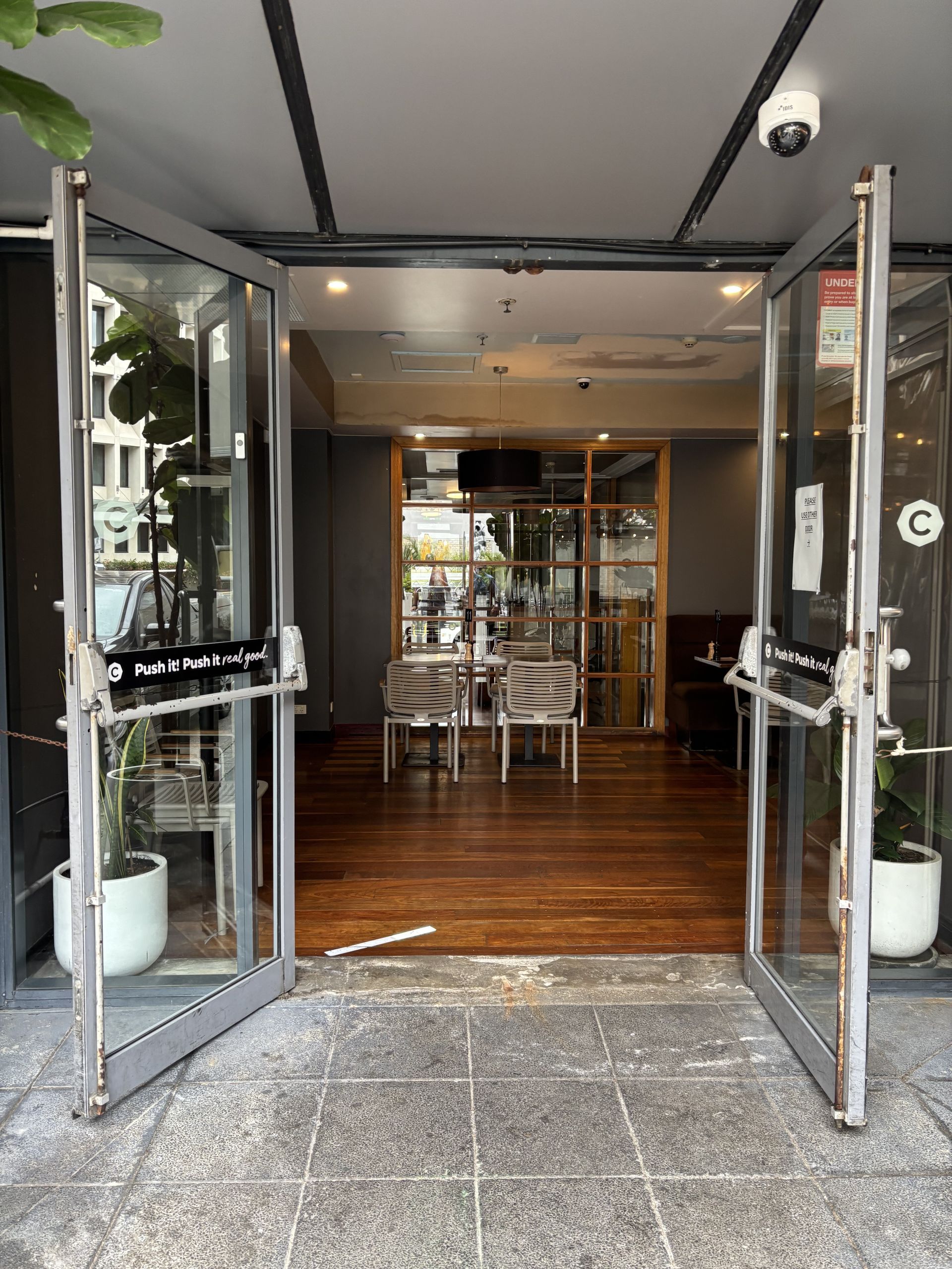 Open glass doors leading into a restaurant with tables and chairs; wooden floor— Fix-A-Door in Morisset, NSW