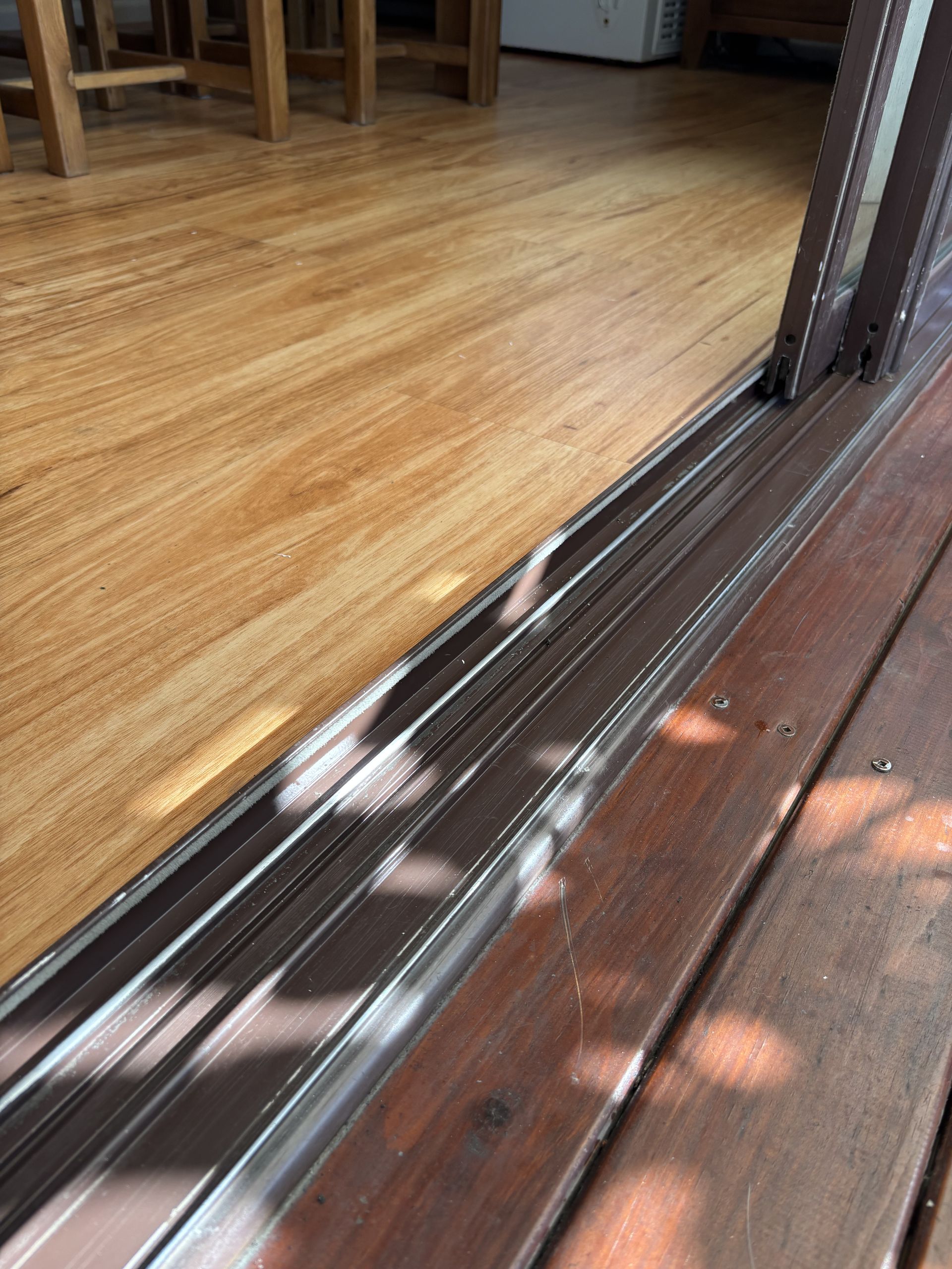 Wooden Floor Meets A Brown Metal Sliding Door — Fix-A-Door in Raymond Terrace, NSW