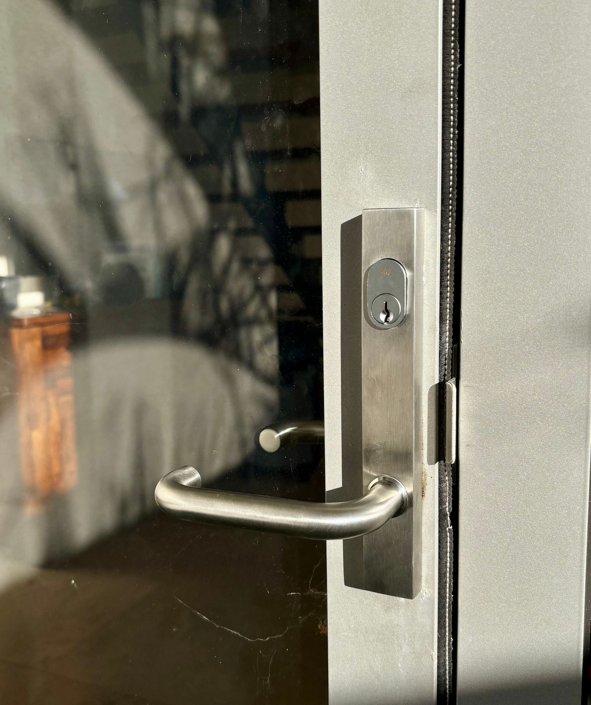 Silver Door Handle With A Keyhole On A Glass Door — Fix-A-Door in Cessnock, NSW