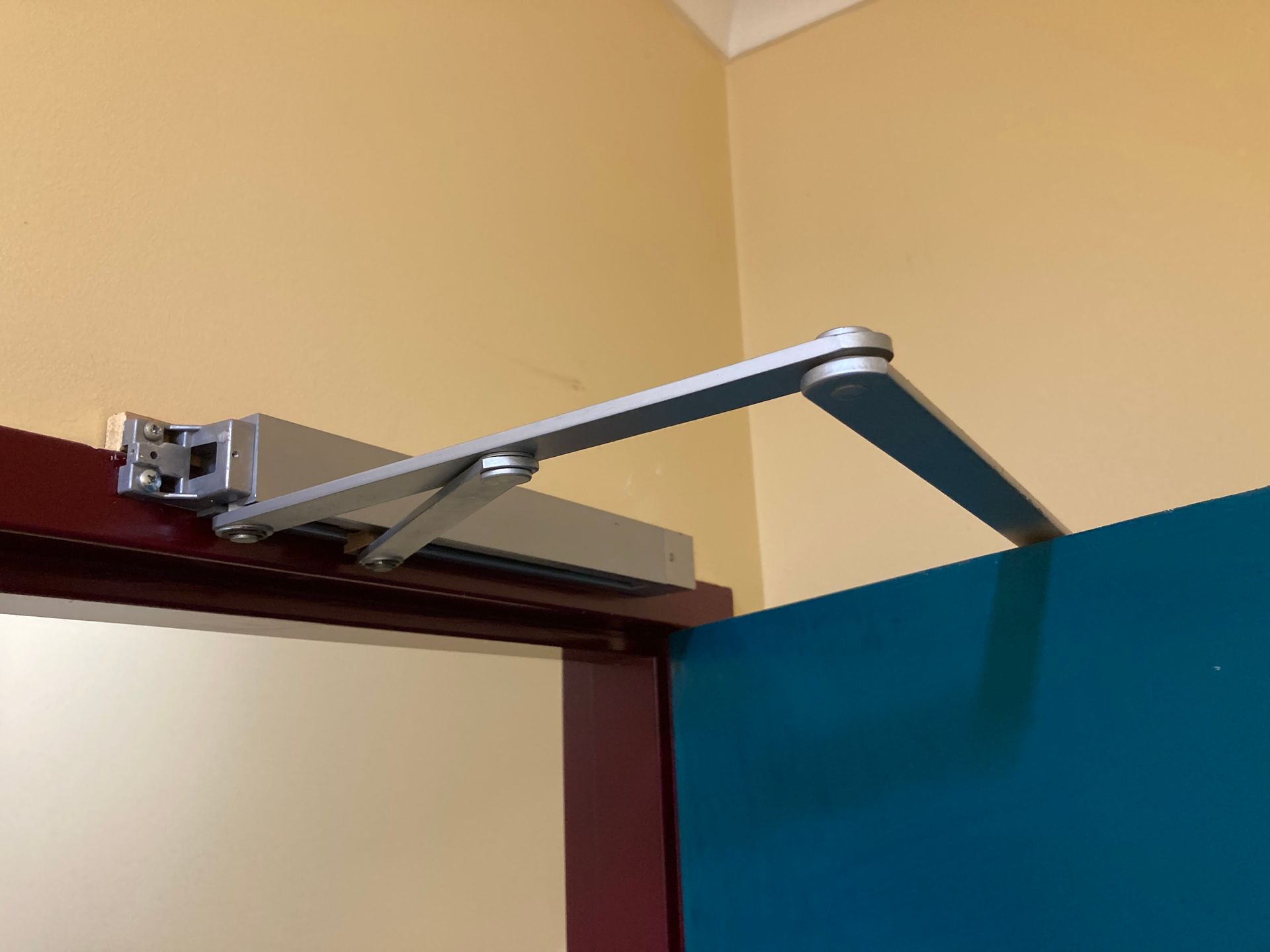 Silver Door Closer Mechanism Installed Above A Door — Fix-A-Door in Wyong, NSW