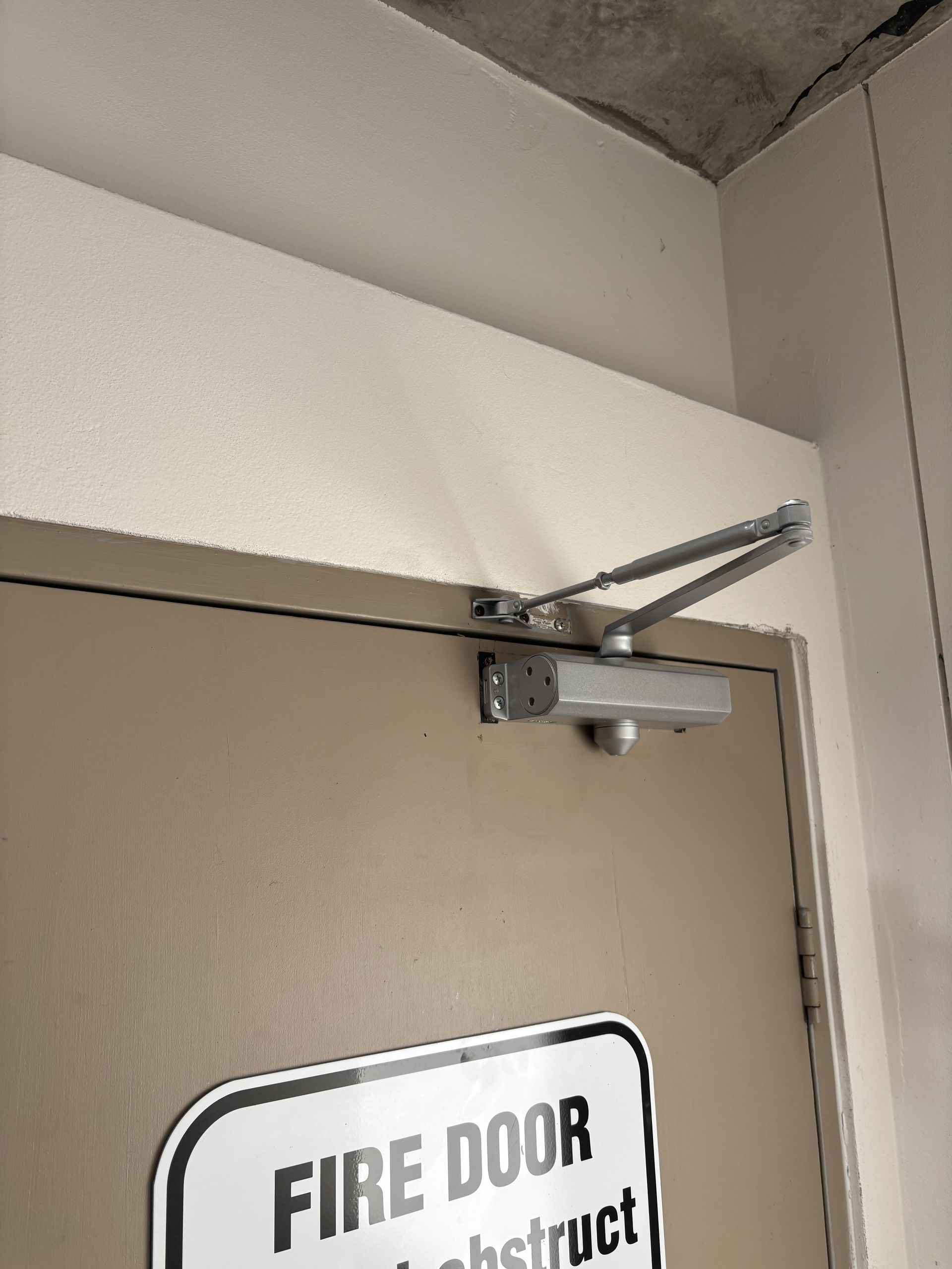 Tan Fire Door With A Silver Door Closer — Fix-A-Door in Wyong, NSW